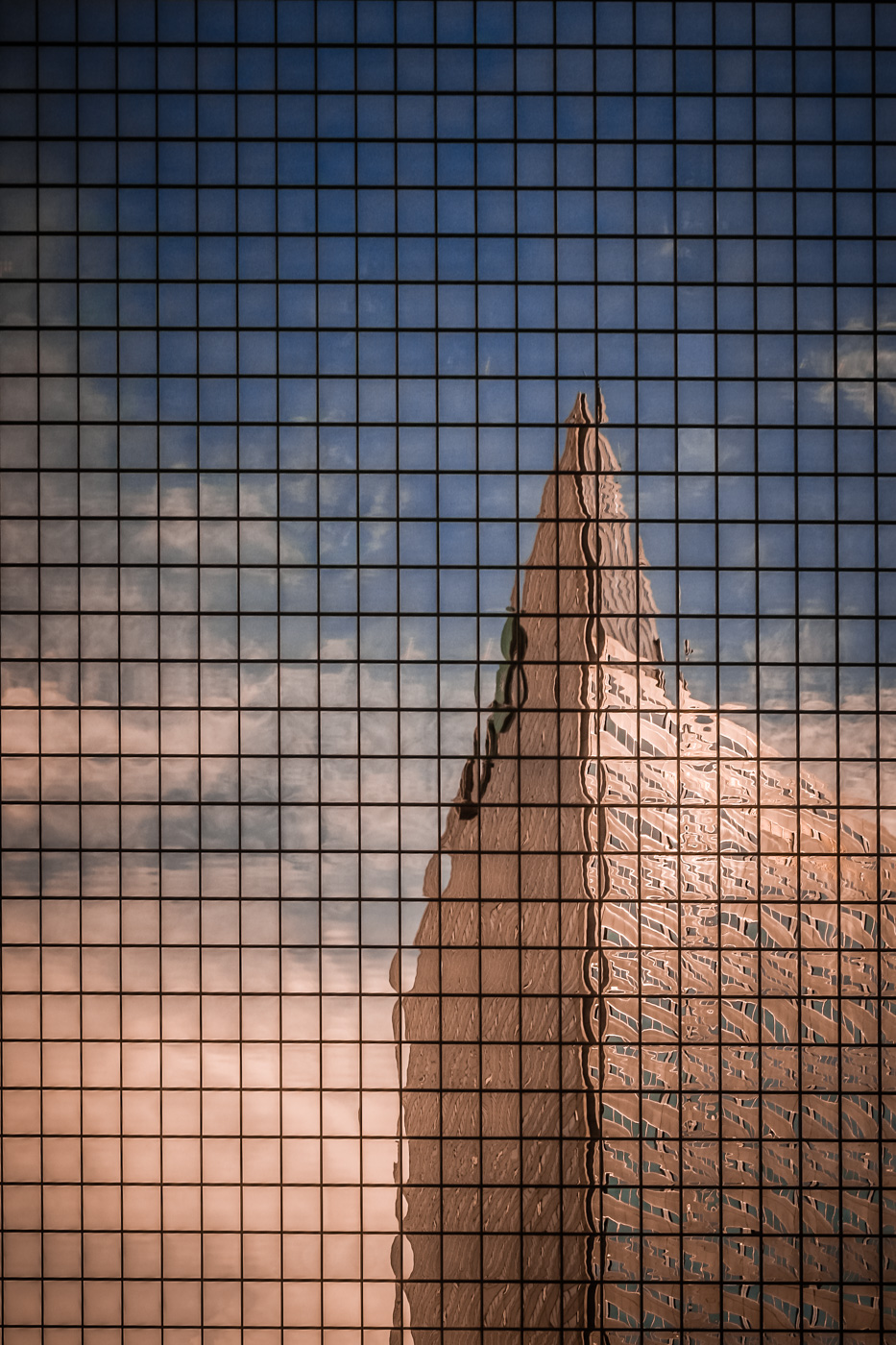Downtown Dallas' Energy Plaza, reflected in an adjacent skyscraper's windows.
