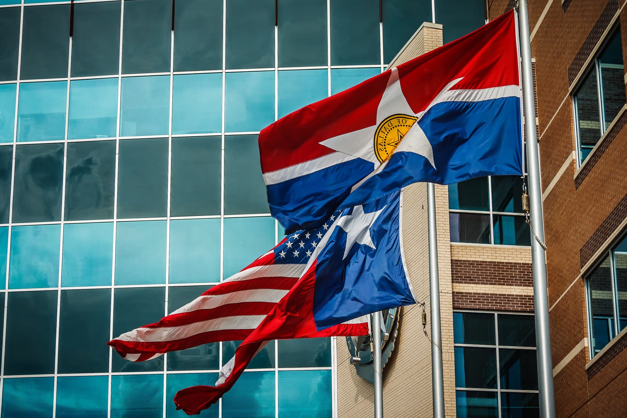 The flags of the City of Dallas, Texas and the United States wave in the wind outside of the Dallas Police Department Headquarters in The Cedars.