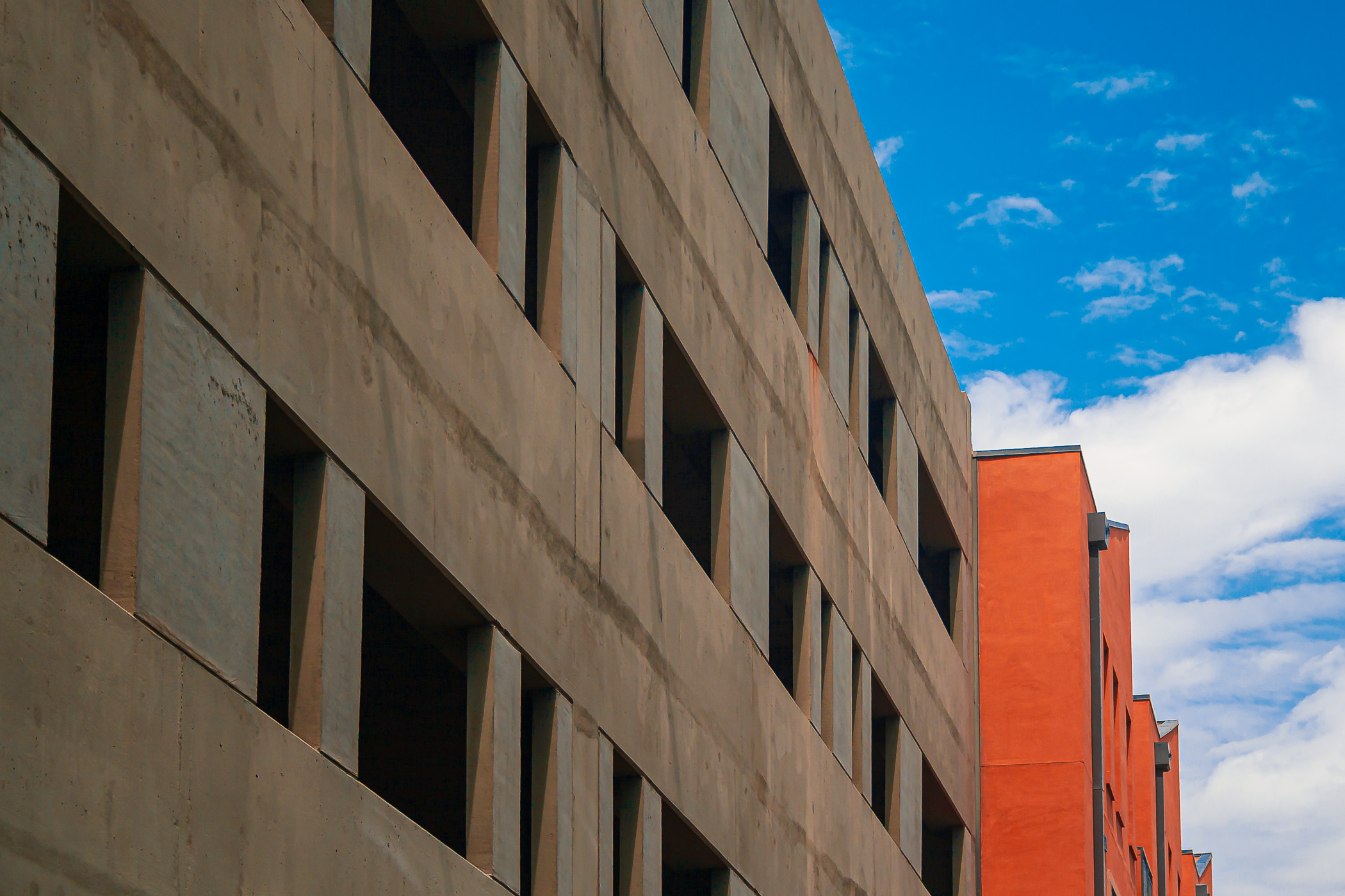 One of the parking garages at Eastside Village in downtown Plano, Texas, next to a bright orange residential building. One of the parking garages at Eastside Village in downtown Plano, Texas, next to a bright orange residential building.