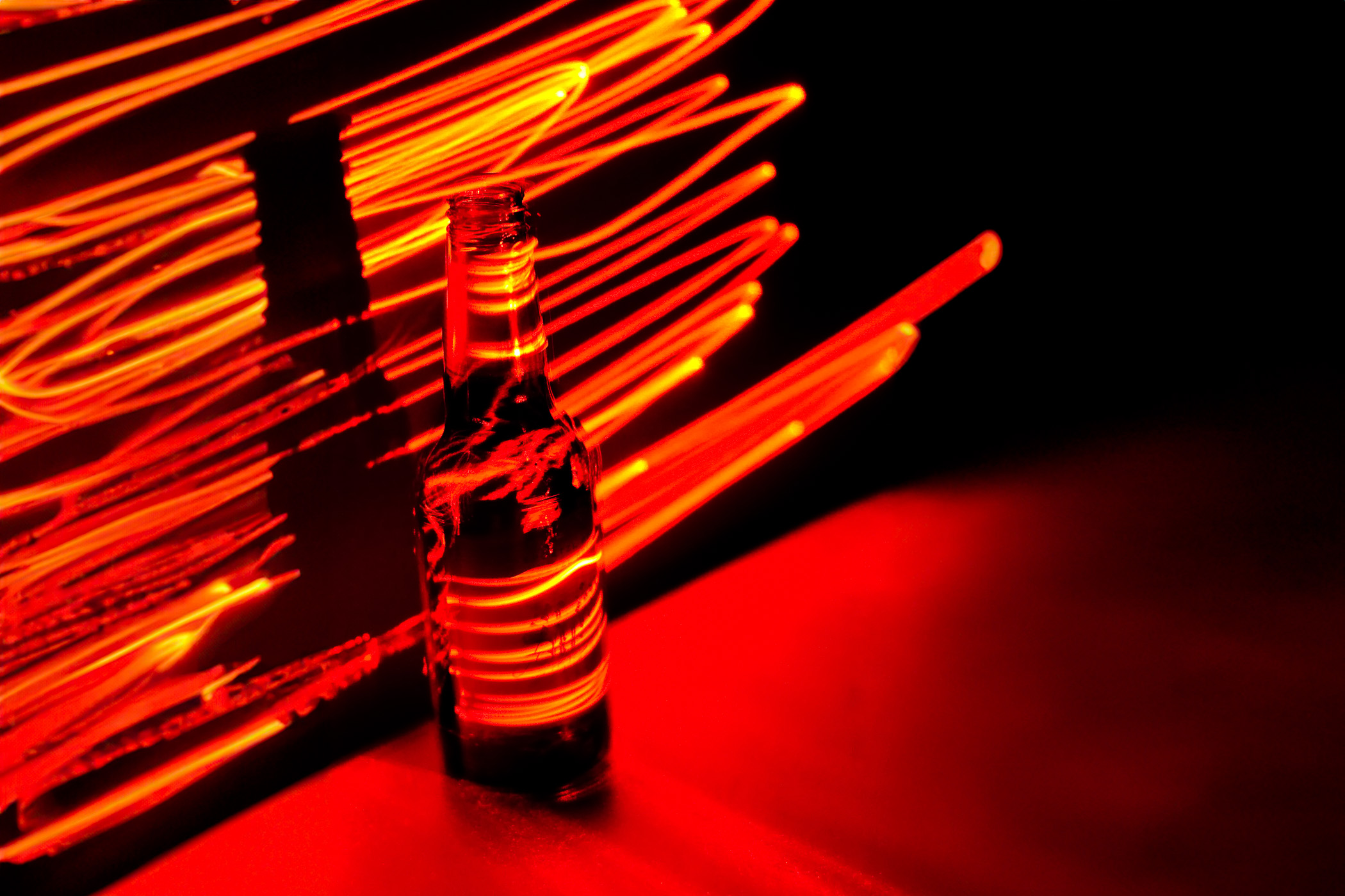 A Shiner Bock beer bottle illuminated by a laser pointer in a long-exposure shot.