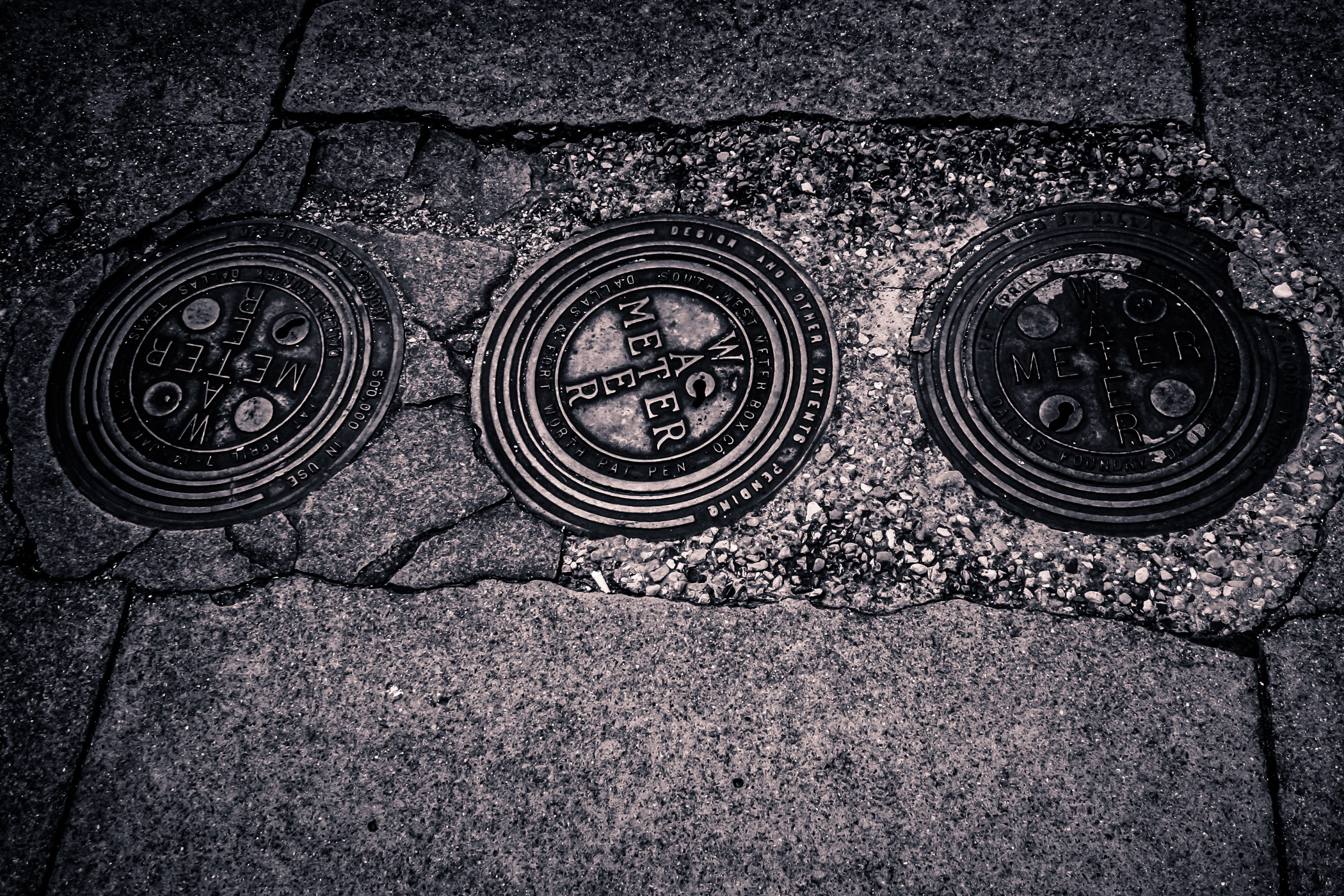 Three water meters embedded in the sidewalk in Downtown Tyler, Texas.