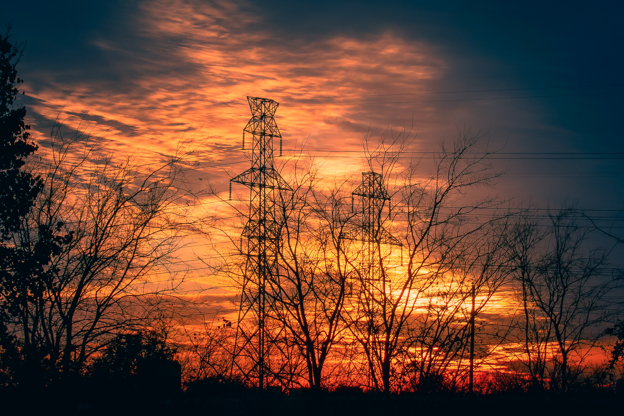 The sun sets behind electric towers in Far North Dallas.