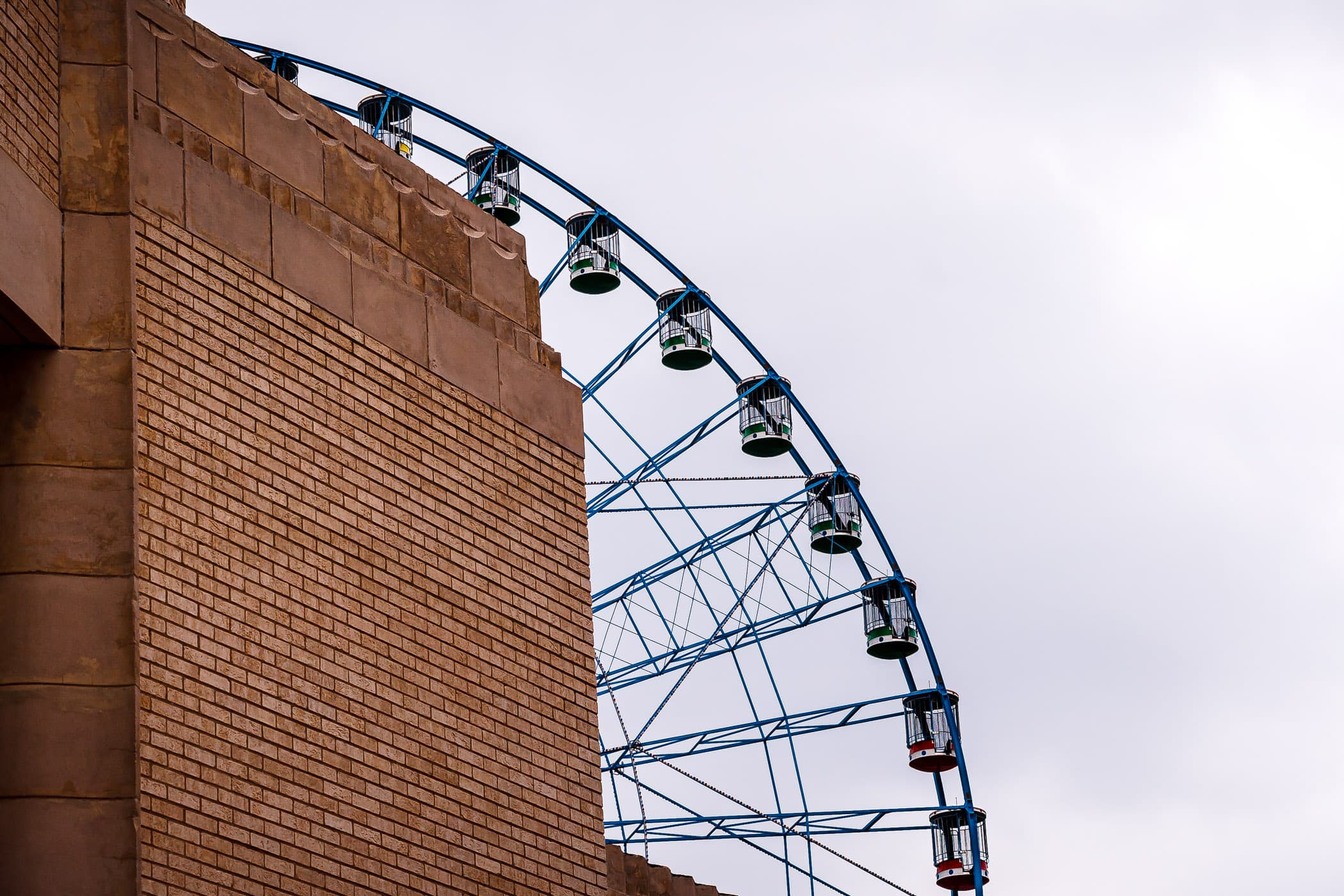 The Texas Star Ferris wheel peeks out from behind a wall of an adjacent building at Fair Park, Dallas.