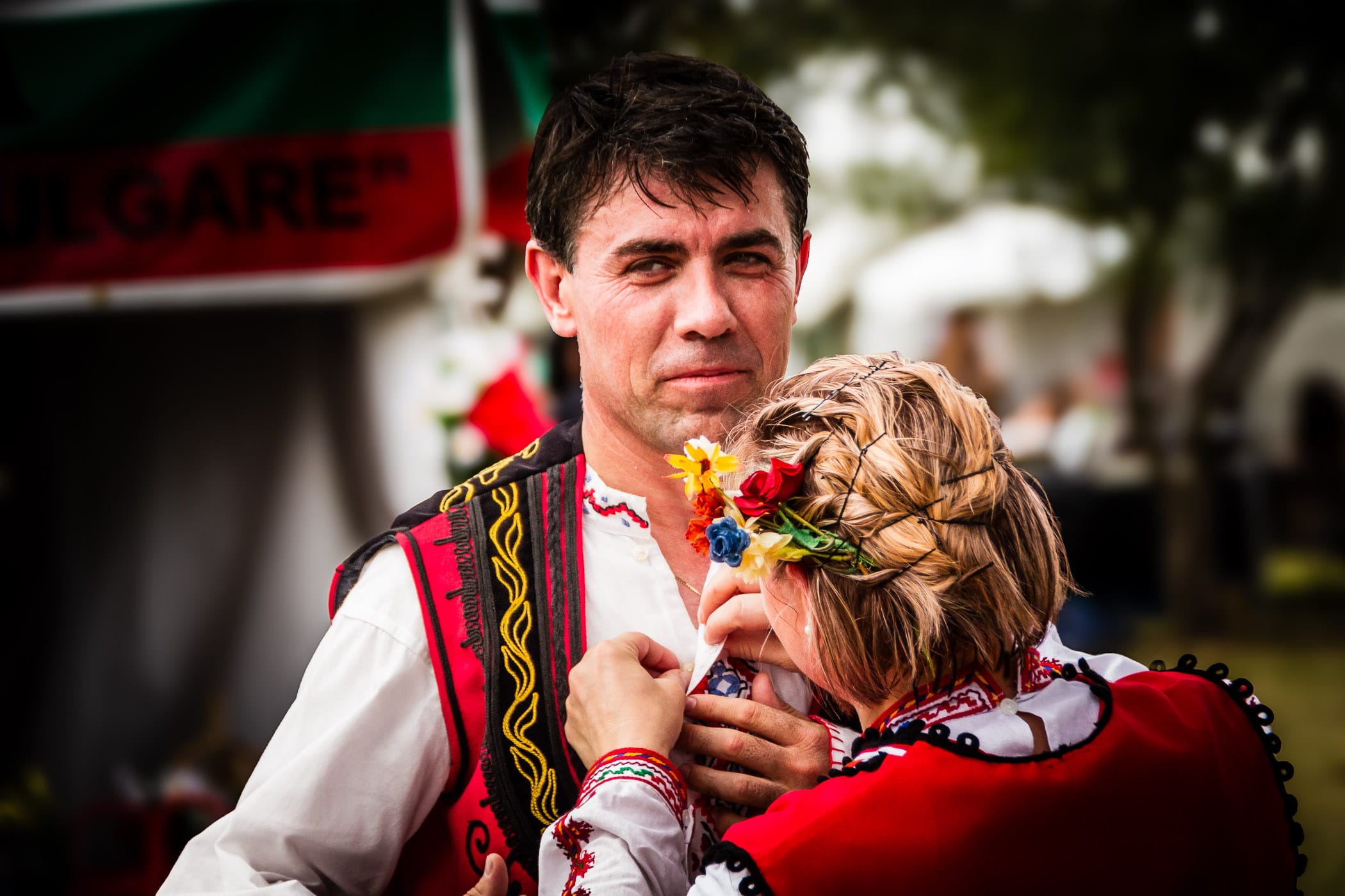 A Bulgarian dancer's traditional costume is adjusted by his companion at Addison Worldfest, Addison, Texas.