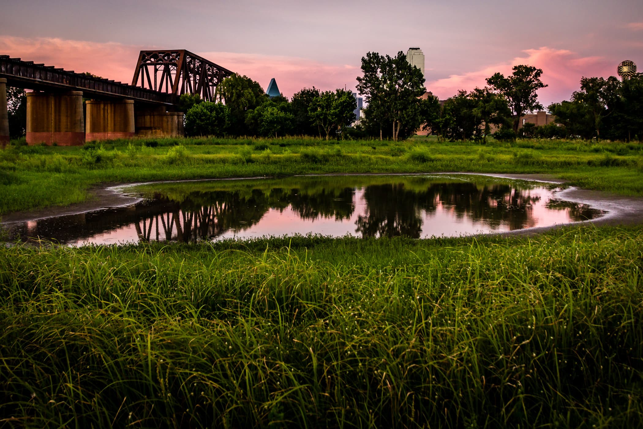A railroad bridge over the Trinity River just west of Downtown Dallas, as seen just before sunset.