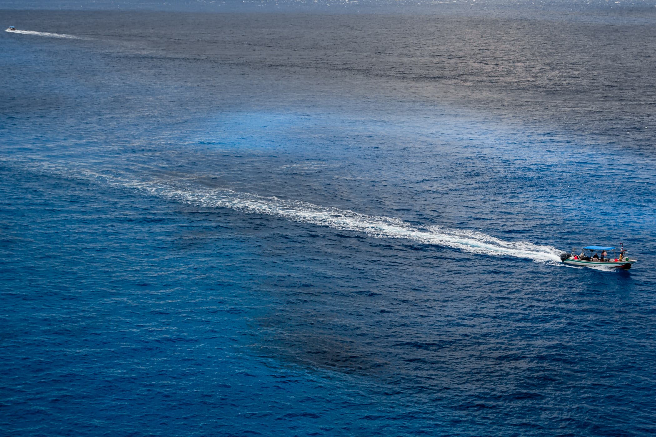 A boat cuts through blue waters just off the coast of Cozumel, Mexico.