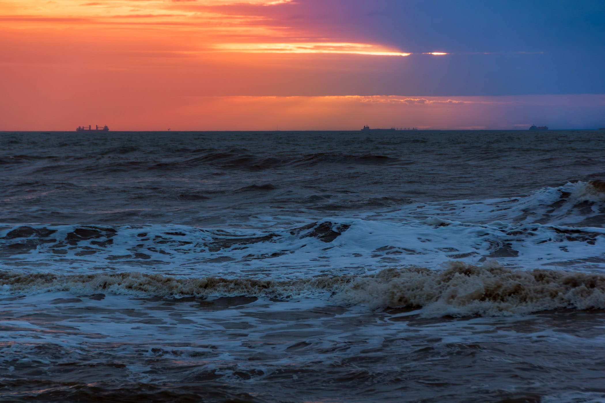 Ships off the shore of Galveston, Texas as the sun rises over the Gulf of Mexico.