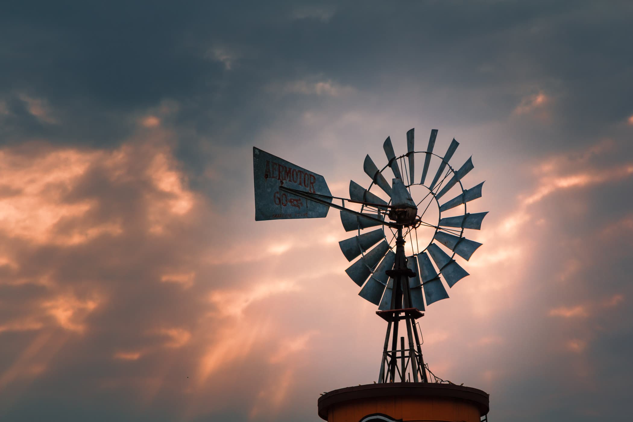 Sun rays pierce the clouds and illuminate a windmill in Downtown Grapevine, Texas.