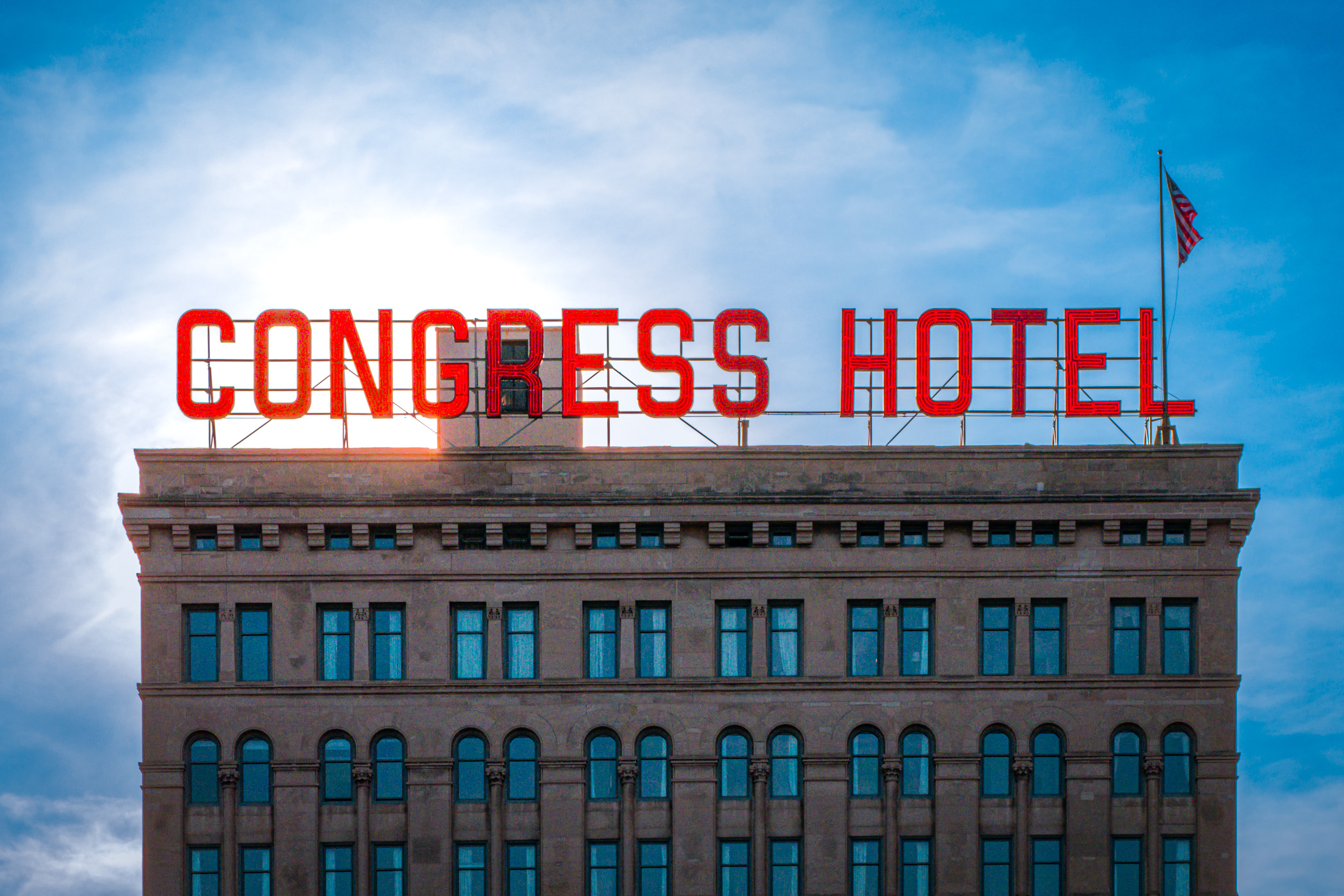 The sun begins to set behind Chicago's "most-haunted" hotel, the Congress Plaza Hotel, highlighting its rooftop's red neon sign and American flag.