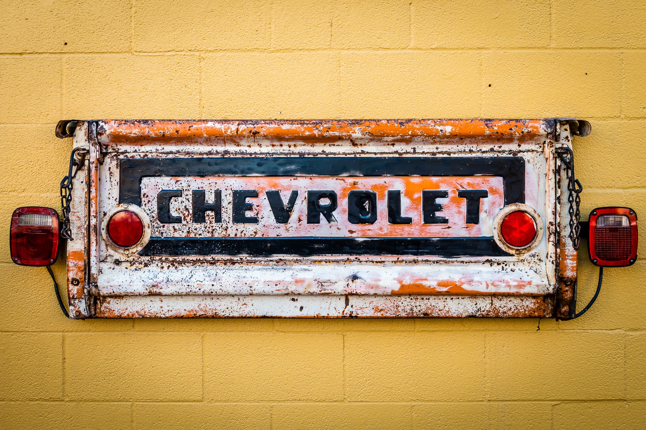 A tailgate from an old Chevrolet pickup truck mounted on a wall as part of the exterior decor of Cajun Tailgators restaurant in Downtown Plano, Texas.