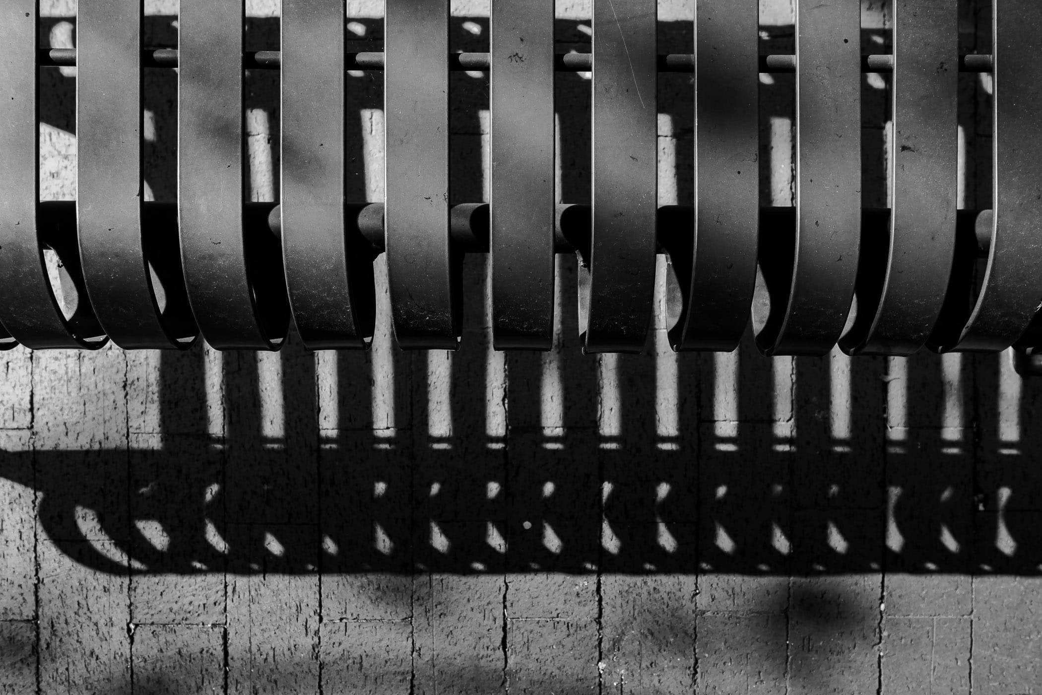 A bench in Downtown Plano, Texas casts a shadow on the brick sidewalk below.