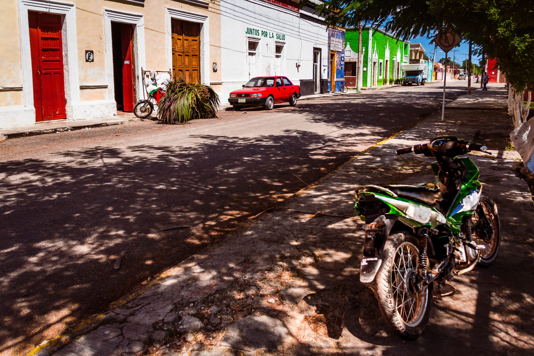 A motorcycle sits in the shade on a street in the village of Dzemul, Yucatan, Mexico.
