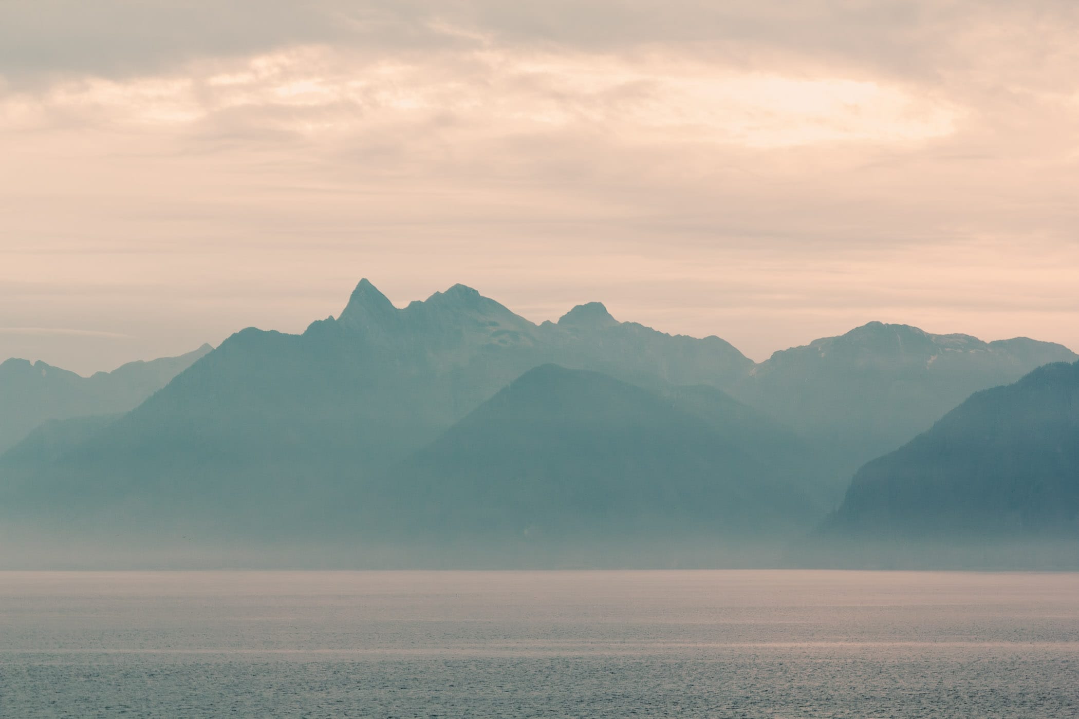 The morning sun lights up the sky beyond the mountain peaks of Alaska's Kuiu Island as seen from Chatham Strait, south of Juneau.