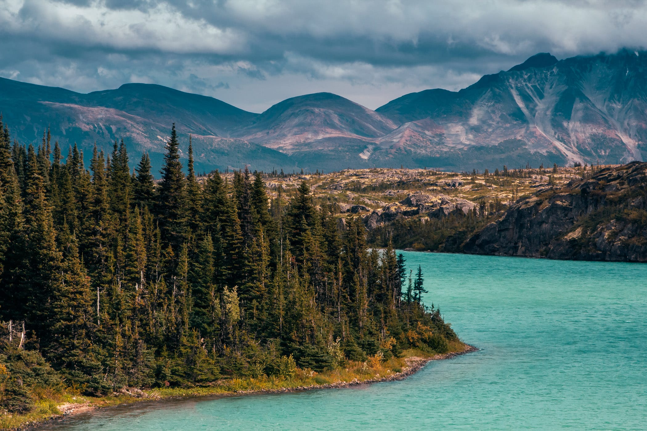 British Columbia's Bernard Lake, surrounded by towering pine trees and mountains along the Klondike Highway.