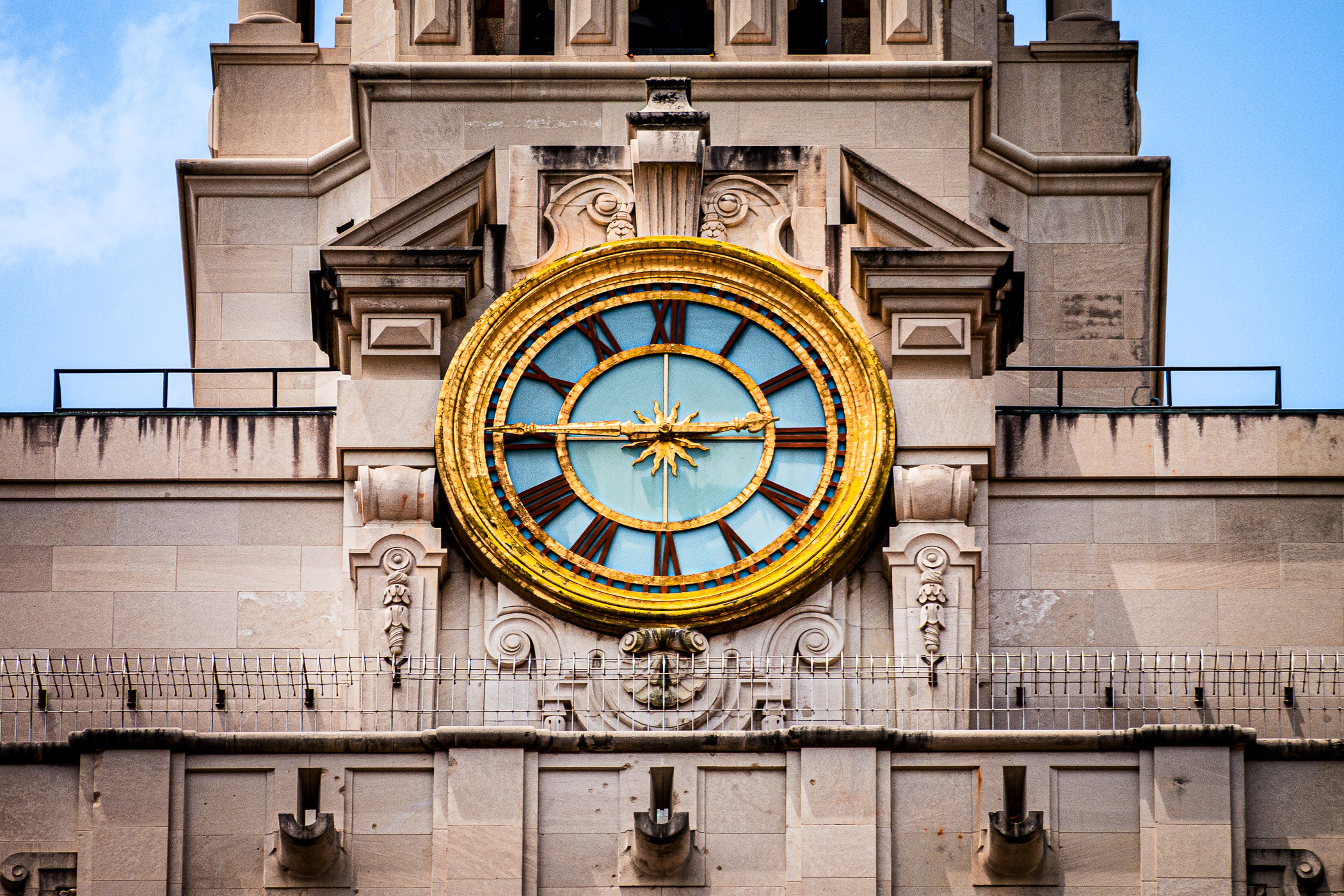 Architectural detail of the clock atop the 307 foot tall Main Building at the University of Texas at Austin. Along the bottom of the image, one can see bullet holes from police officers returning the fire of mass murderer Charles Whitman during his 1966 massacre that left 16 people dead and a further 32 injured.