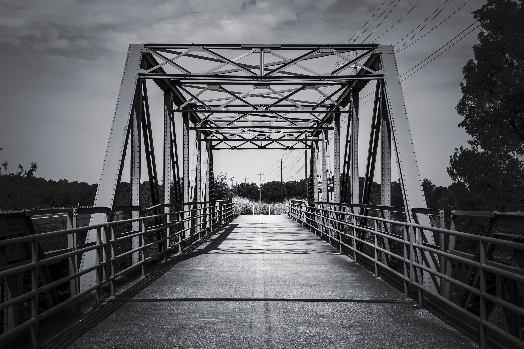 An iron pedestrian bridge spans the Elm Fork of the Trinity River near Aubrey, Texas.