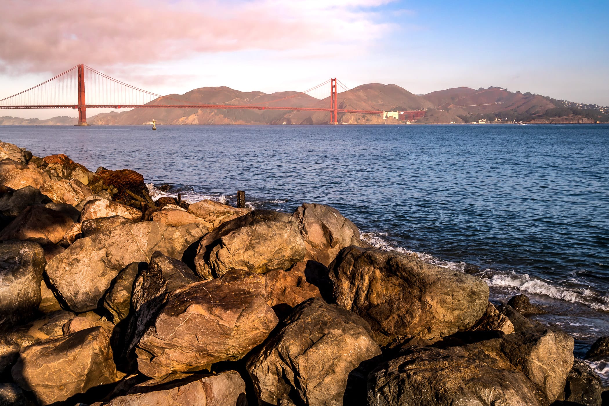 San Francisco's iconic Golden Gate Bridge spans its namesake narrows at the entrance to San Francisco Bay as seen from the rocky shoreline of nearby Crissy Field.