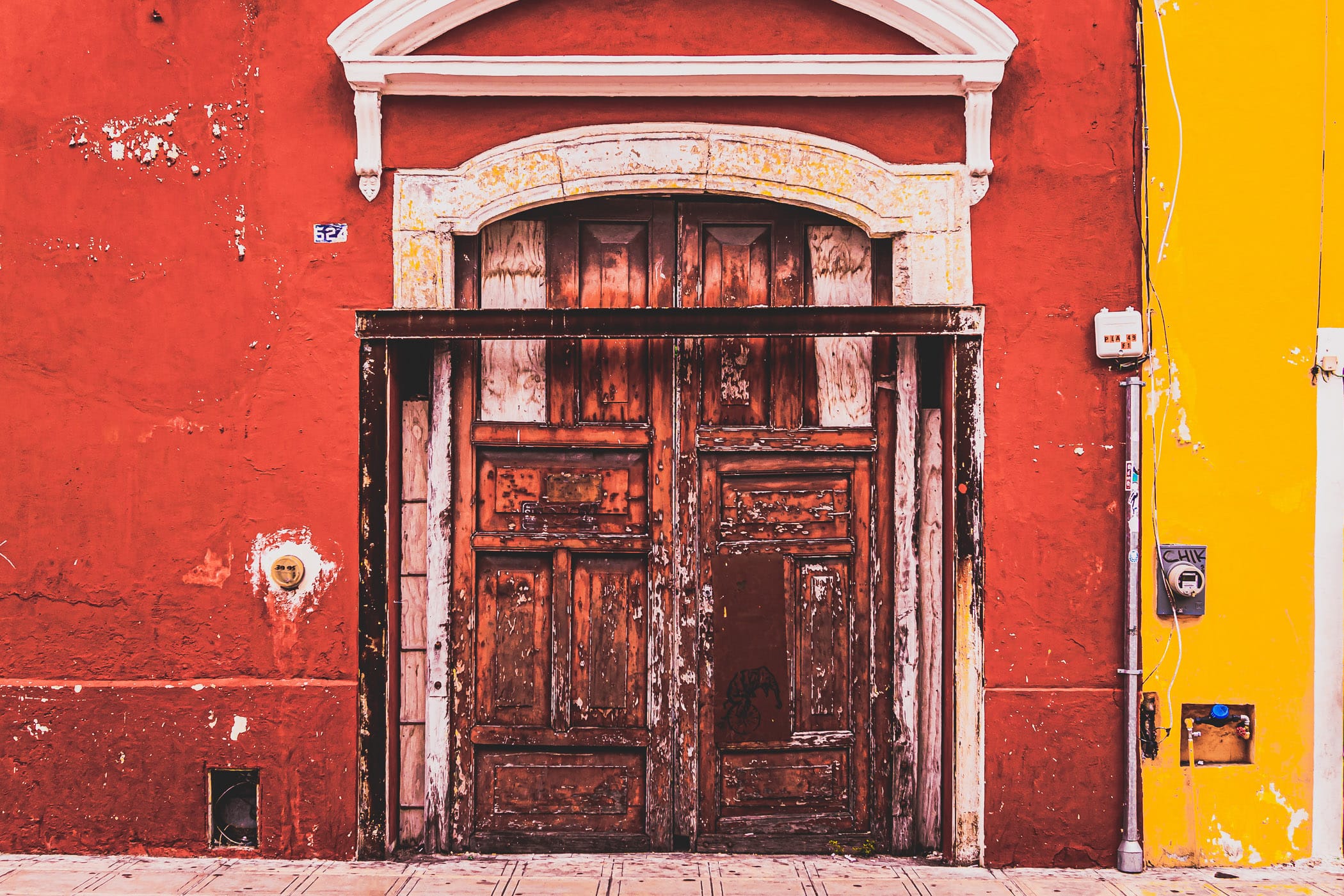 An aged door on a brightly-colored building in Mérida, Yucatán, Mexico.