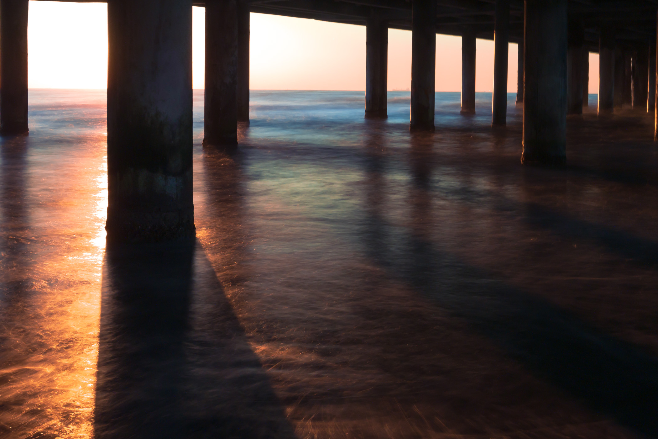 The sun rises as the waters of the Gulf of Mexico swirl around the supporting legs of Galveston, Texas' Historic Pleasure Pier.