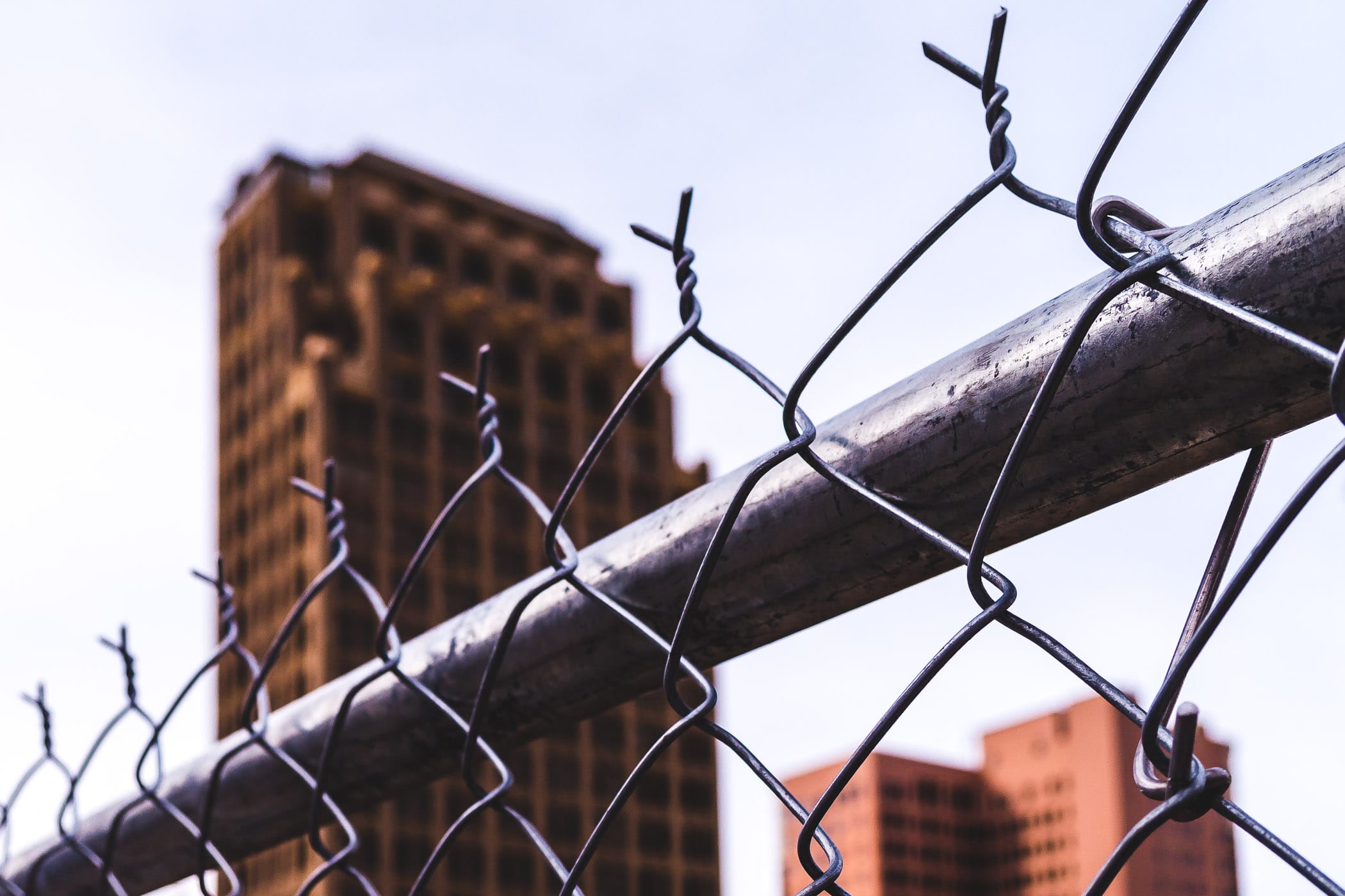 Downtown Houston’s Great Southwest Building rises beyond a neighboring chainlink fence.