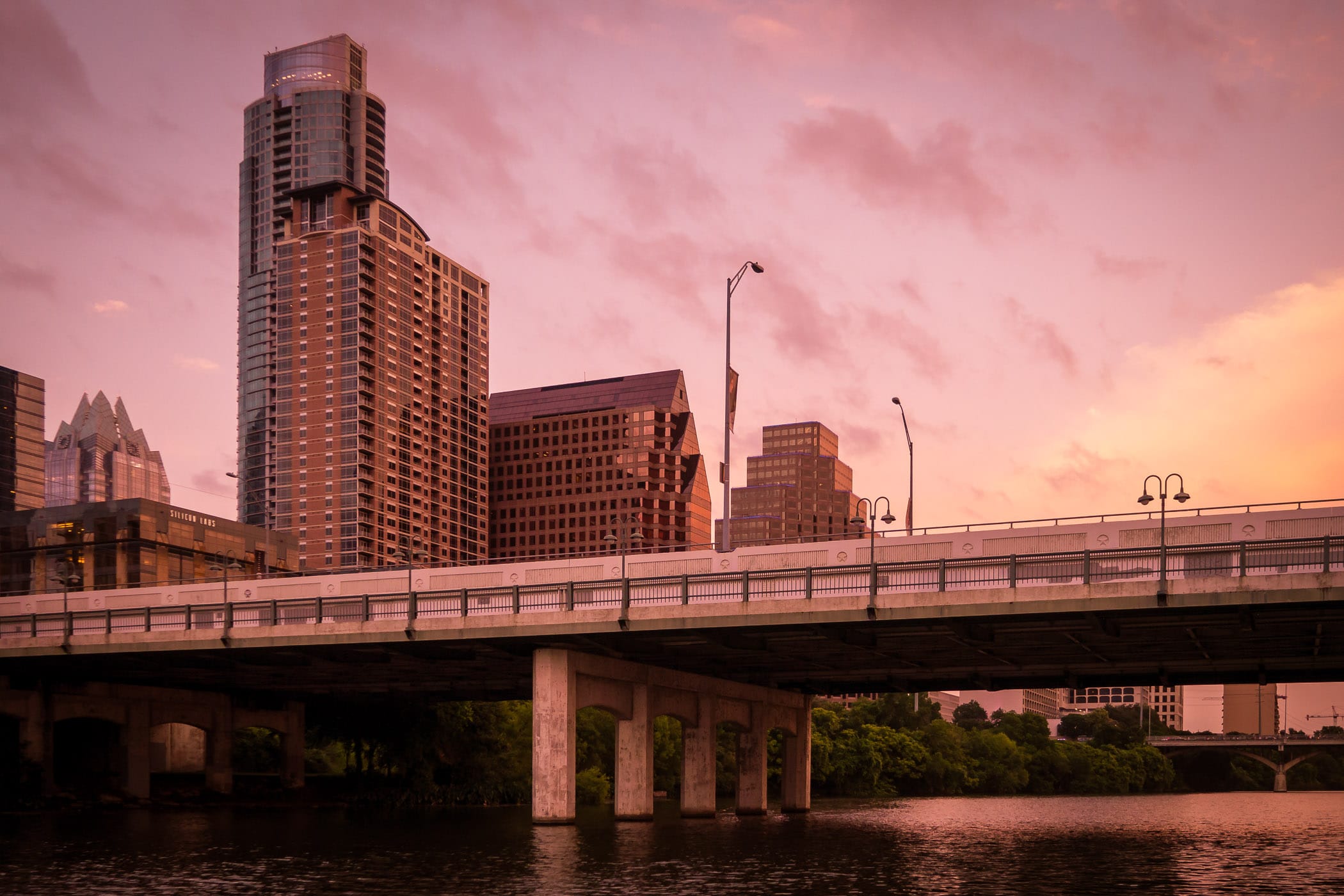 The sun sets on Downtown Austin and the South First Street Bridge as it spans Lady Bird Lake.