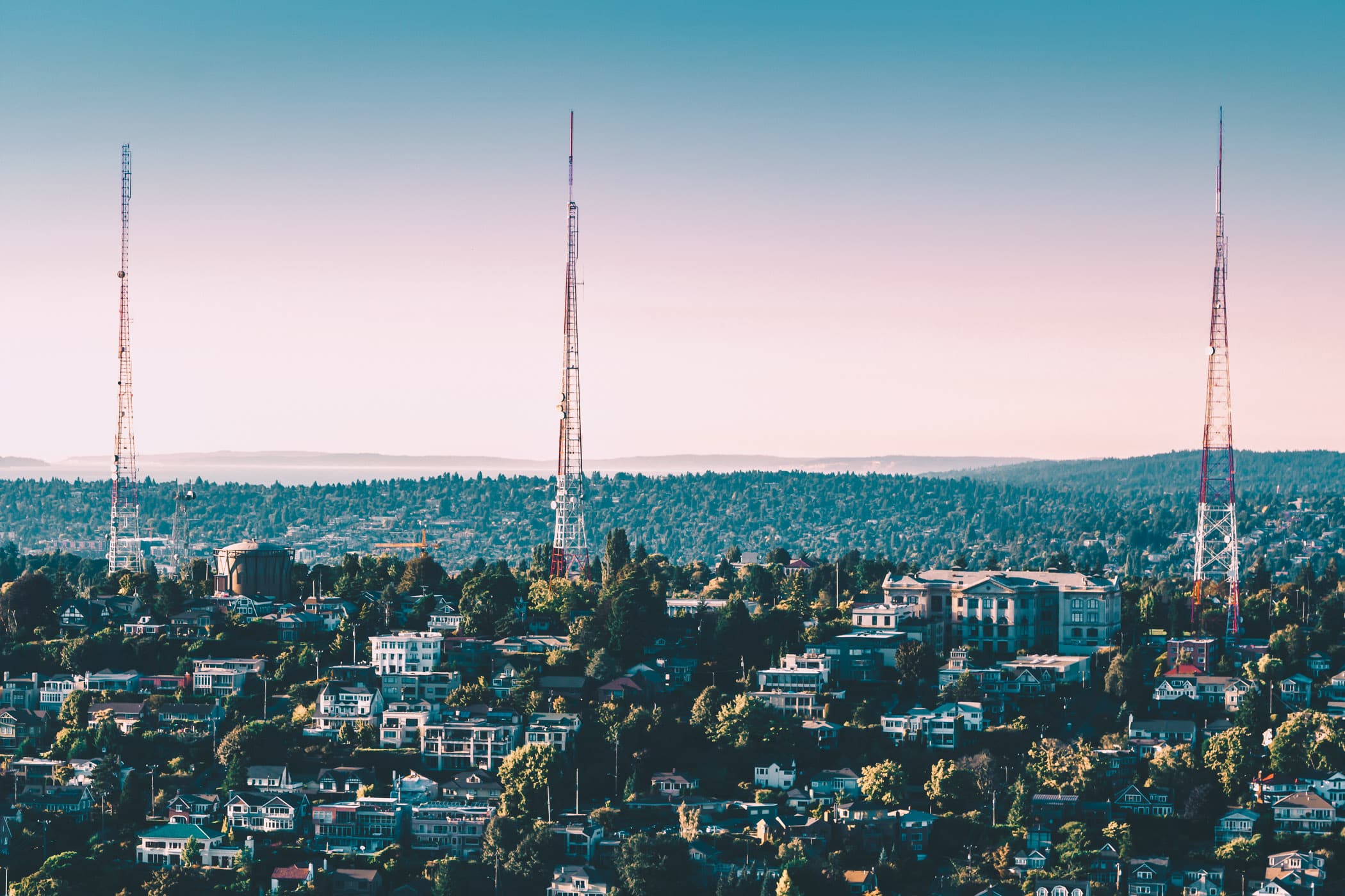 Three broadcast towers rise into the sky as the sun sets on Seattle's Queen Anne neighborhood.