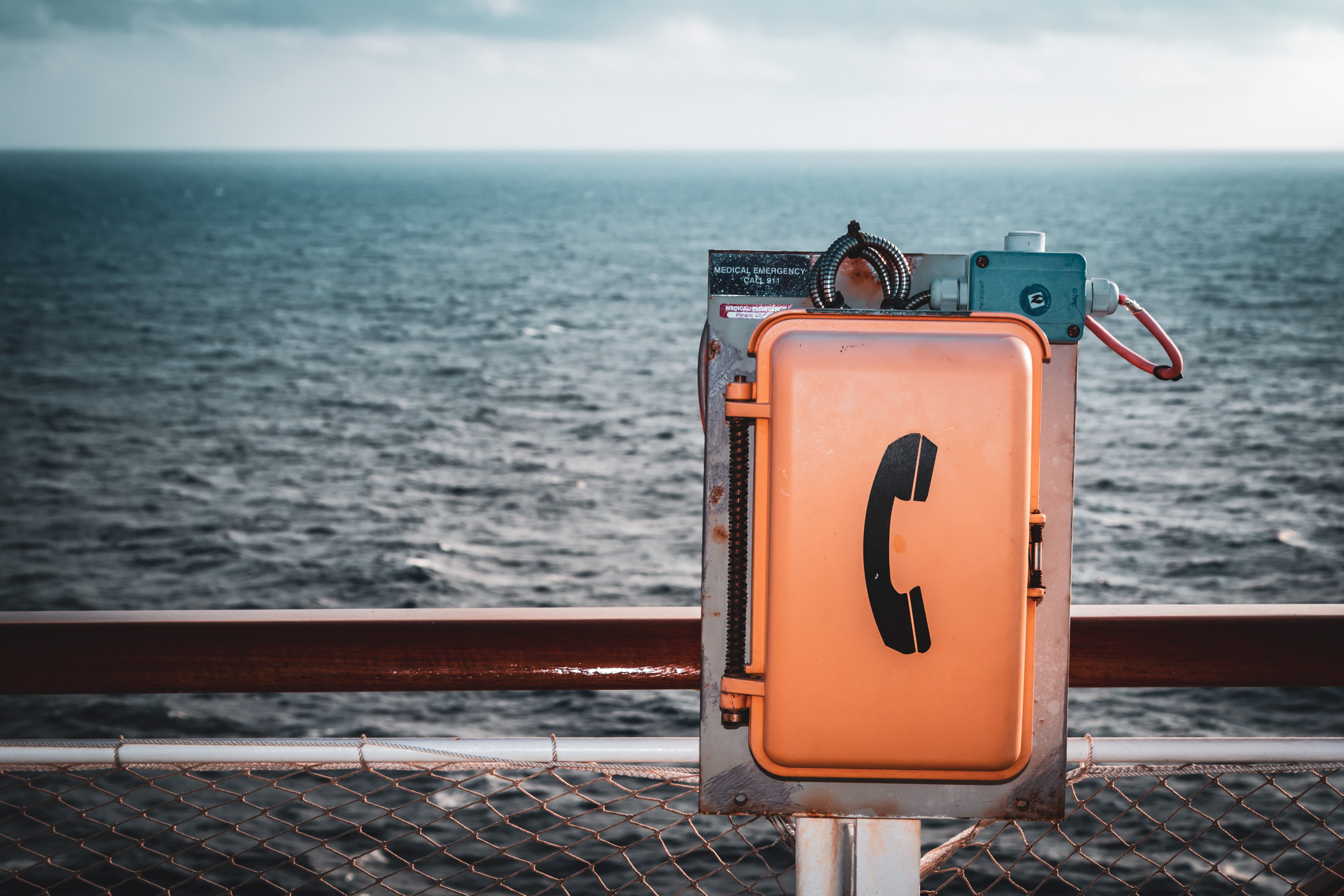 A shipboard telephone box mounted on a railing aboard the cruise ship Carnival Magic.