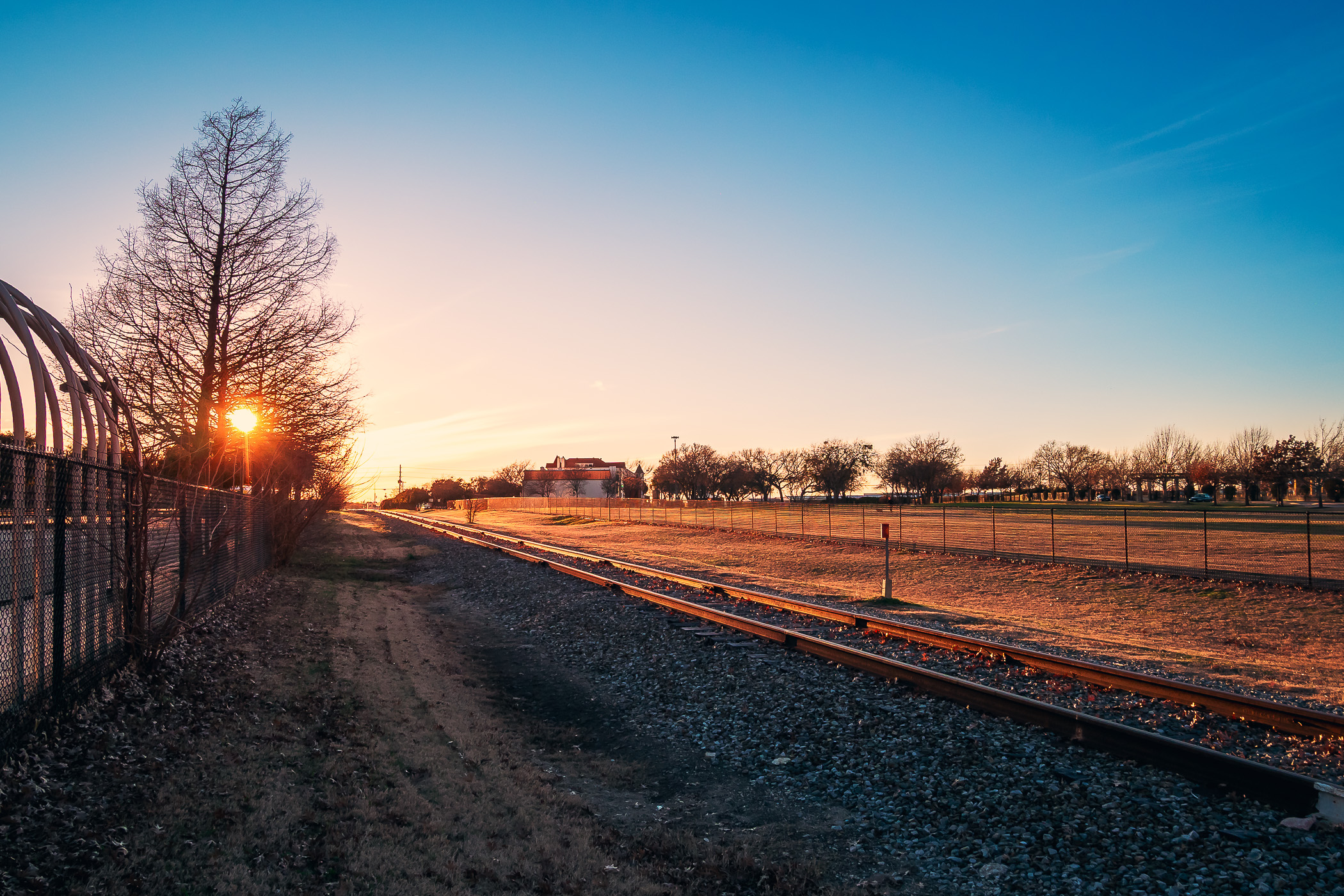 The evening sun illuminates train tracks running through Addison, Texas.