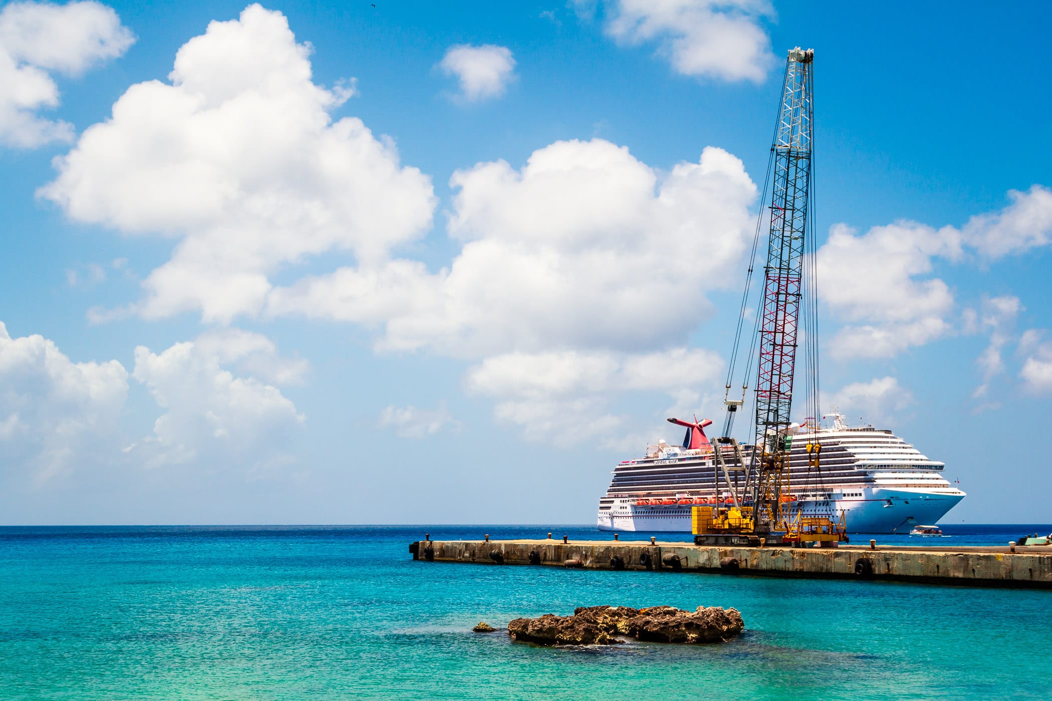 The cruise ship Carnival Magic is obscured by a crane on a nearby pier along the waterfront in George Town, Grand Cayman.