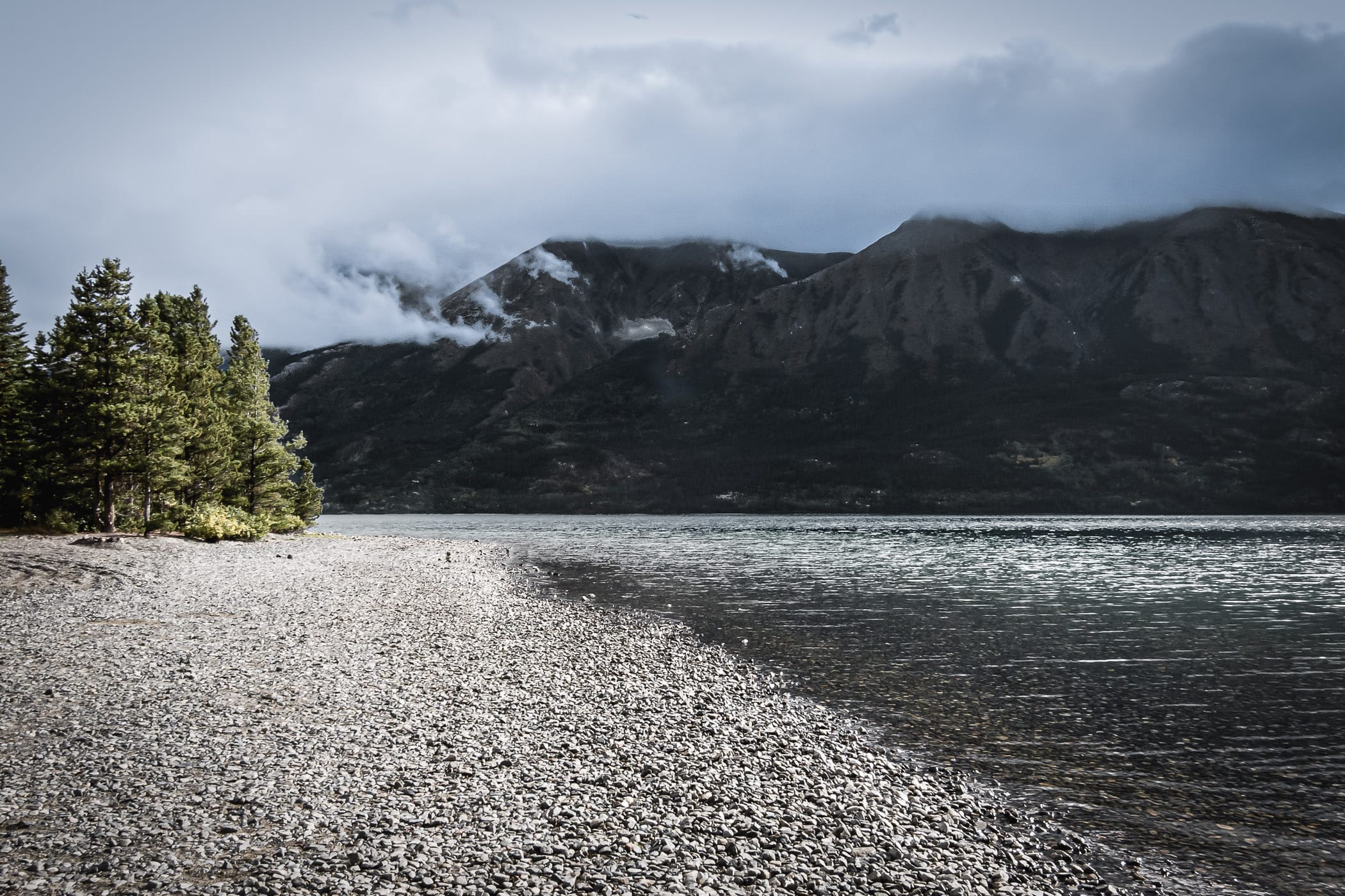 The cloudy, rocky shoreline of British Columbia's Tutshi Lake.