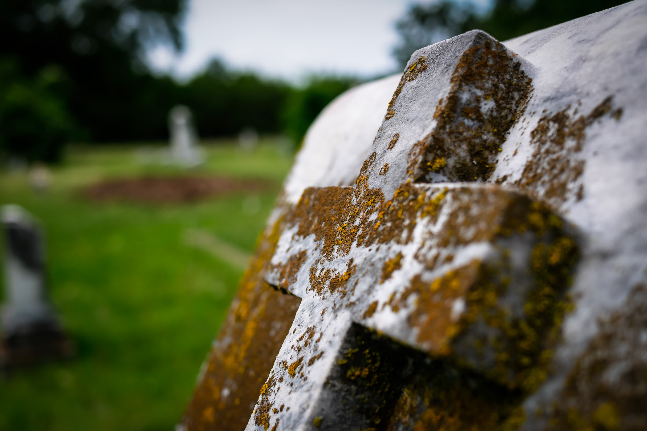 Moss grows on a cross on a headstone in Oakland Memorial Park cemetery, Terrell, Texas.