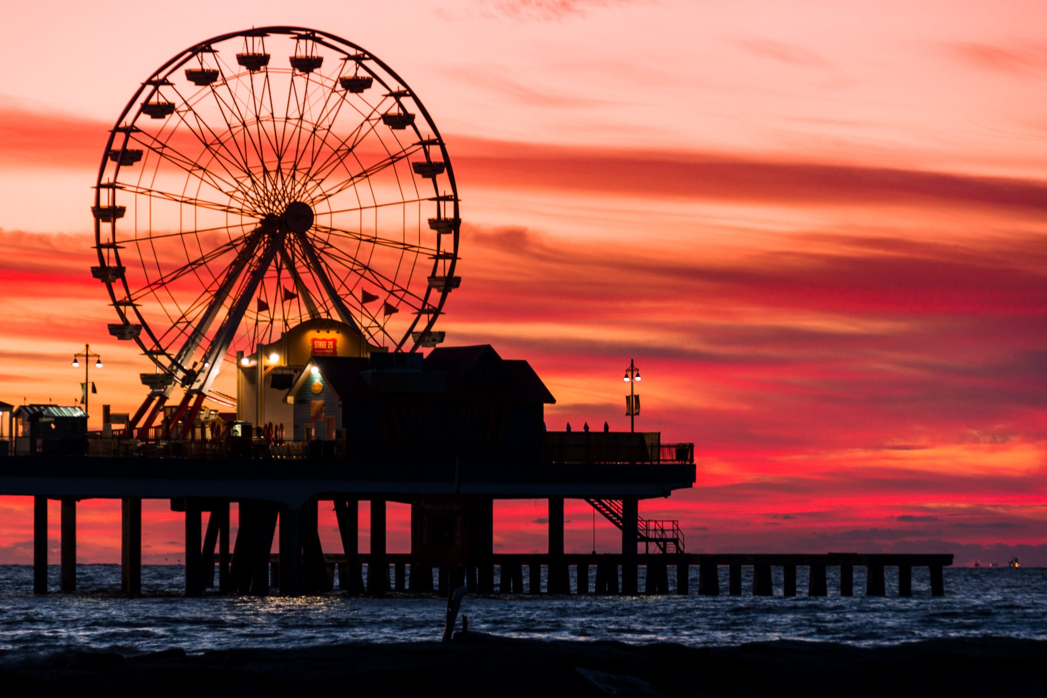 The light of the rising sun silhouettes the Historic Galveston Pleasure Pier as day breaks over the Gulf of Mexico.