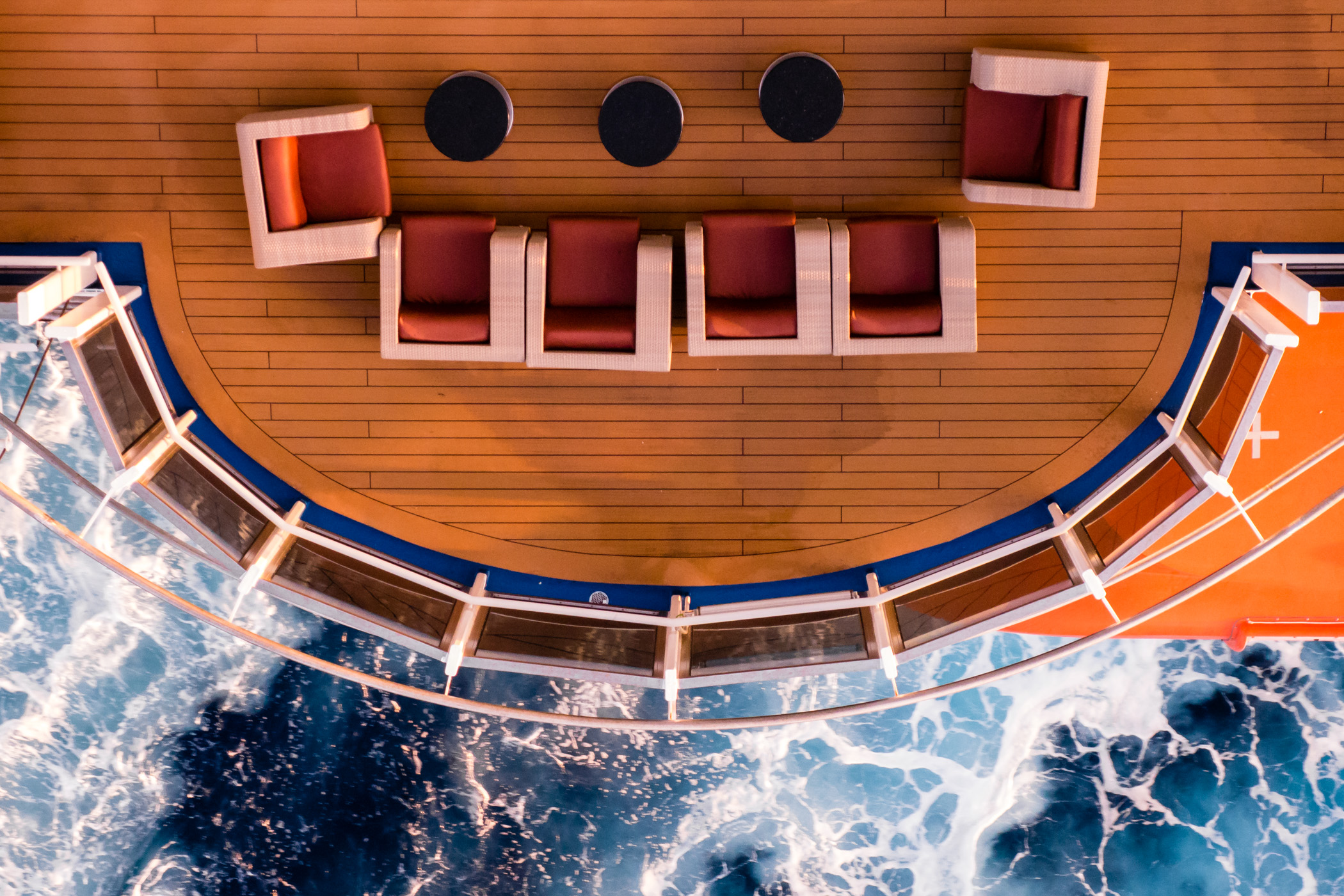 A seating area on the promenade deck of the cruise ship Carnival Magic juts out over the ocean.