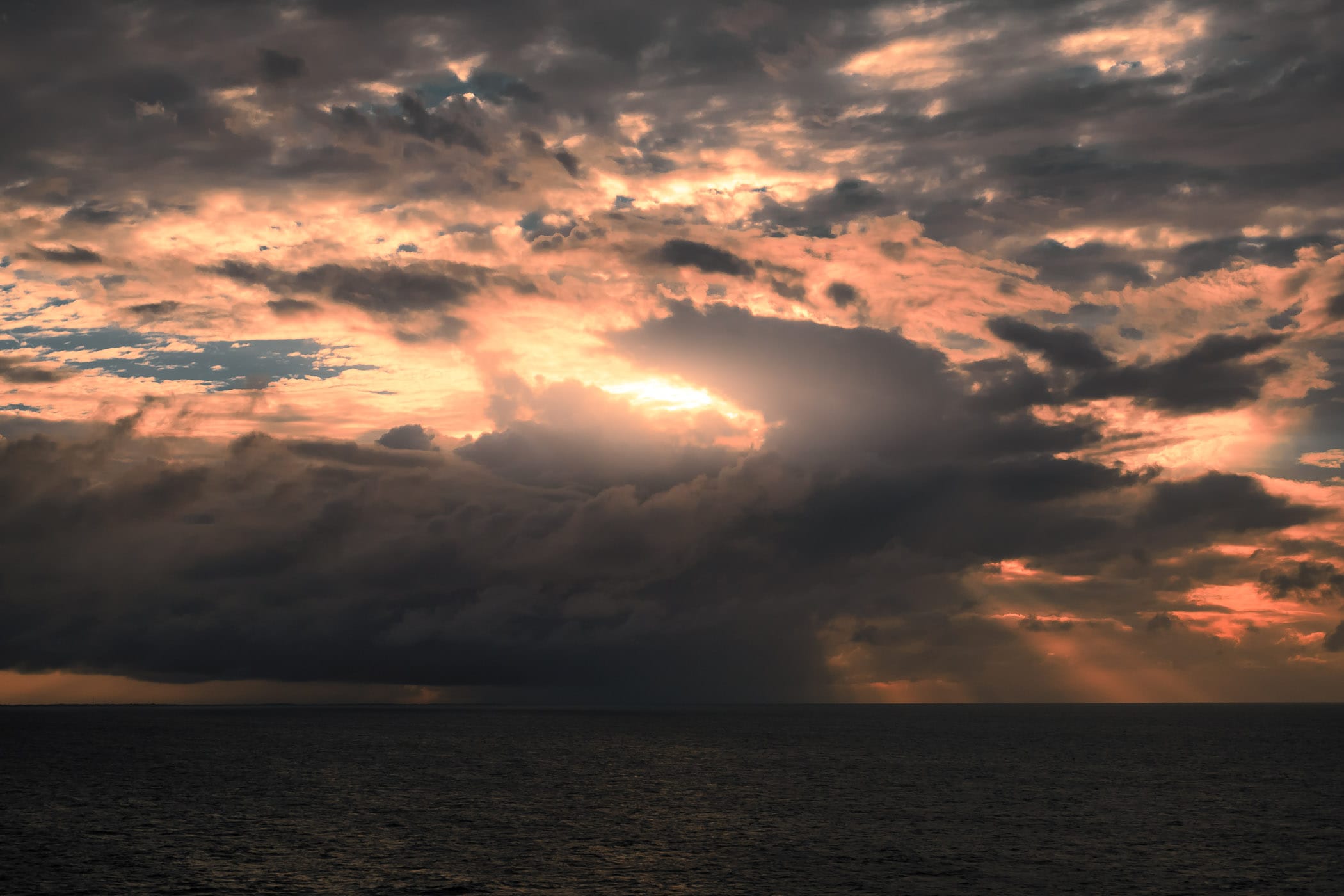 The rising sun silhouettes a rain cloud on the horizon somewhere off the coast of the Yucatan Peninsula in the Gulf of Mexico.