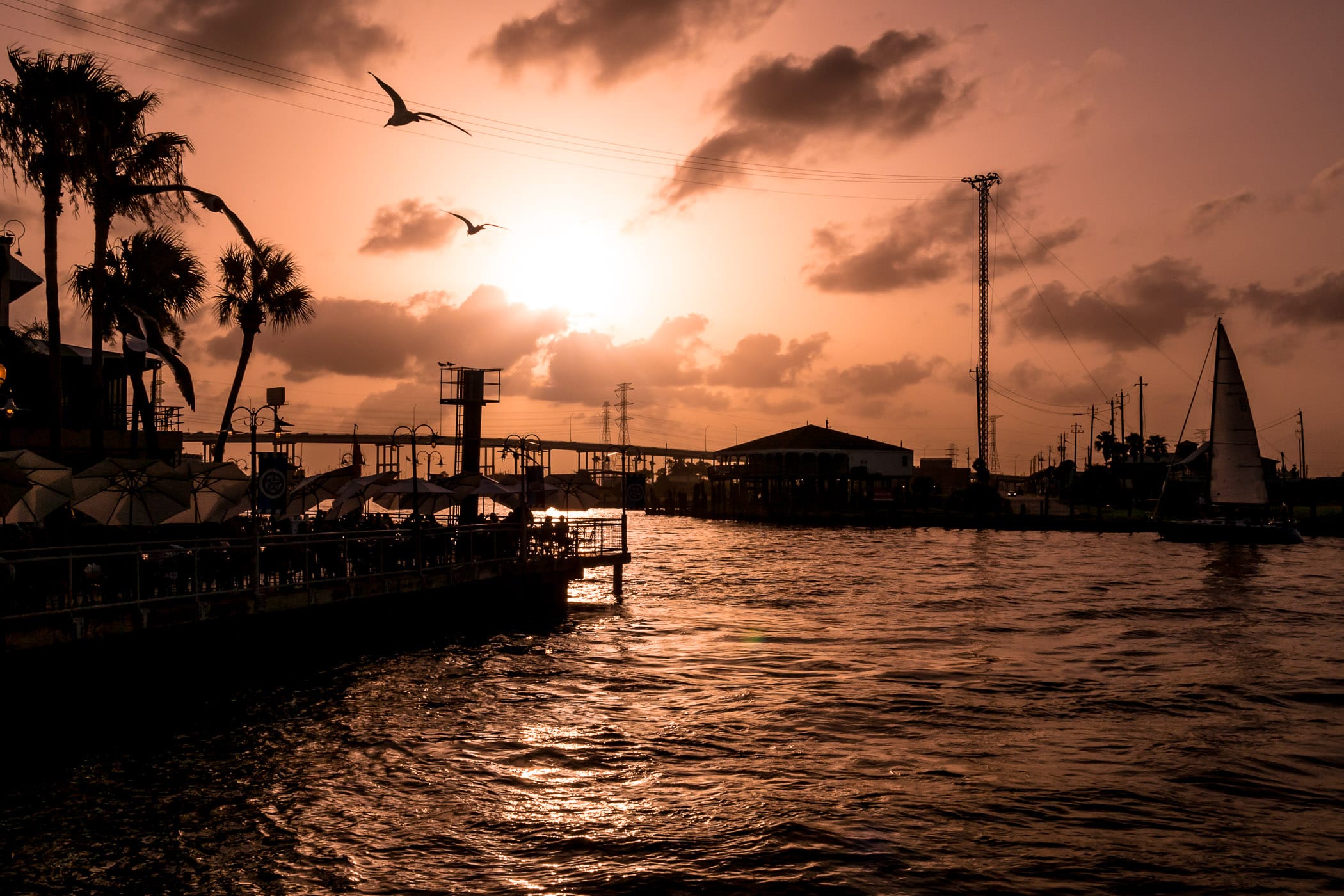 Birds fly by as the sun sets on the Kemah Boardwalk in Kemah, Texas.