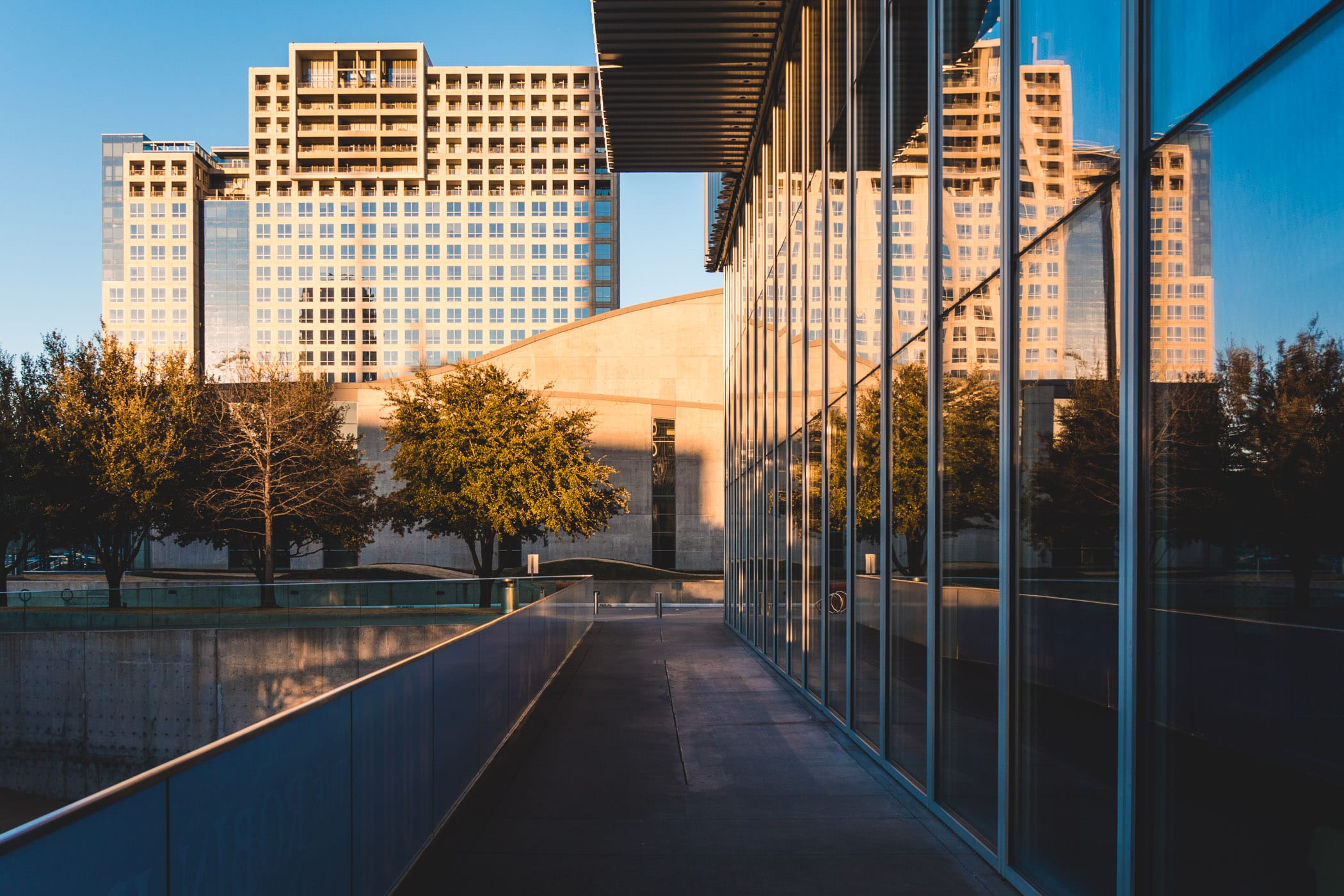 The Dallas Arts District's One Arts Plaza is reflected in the glass facade of the adjacent Wyly Theatre.