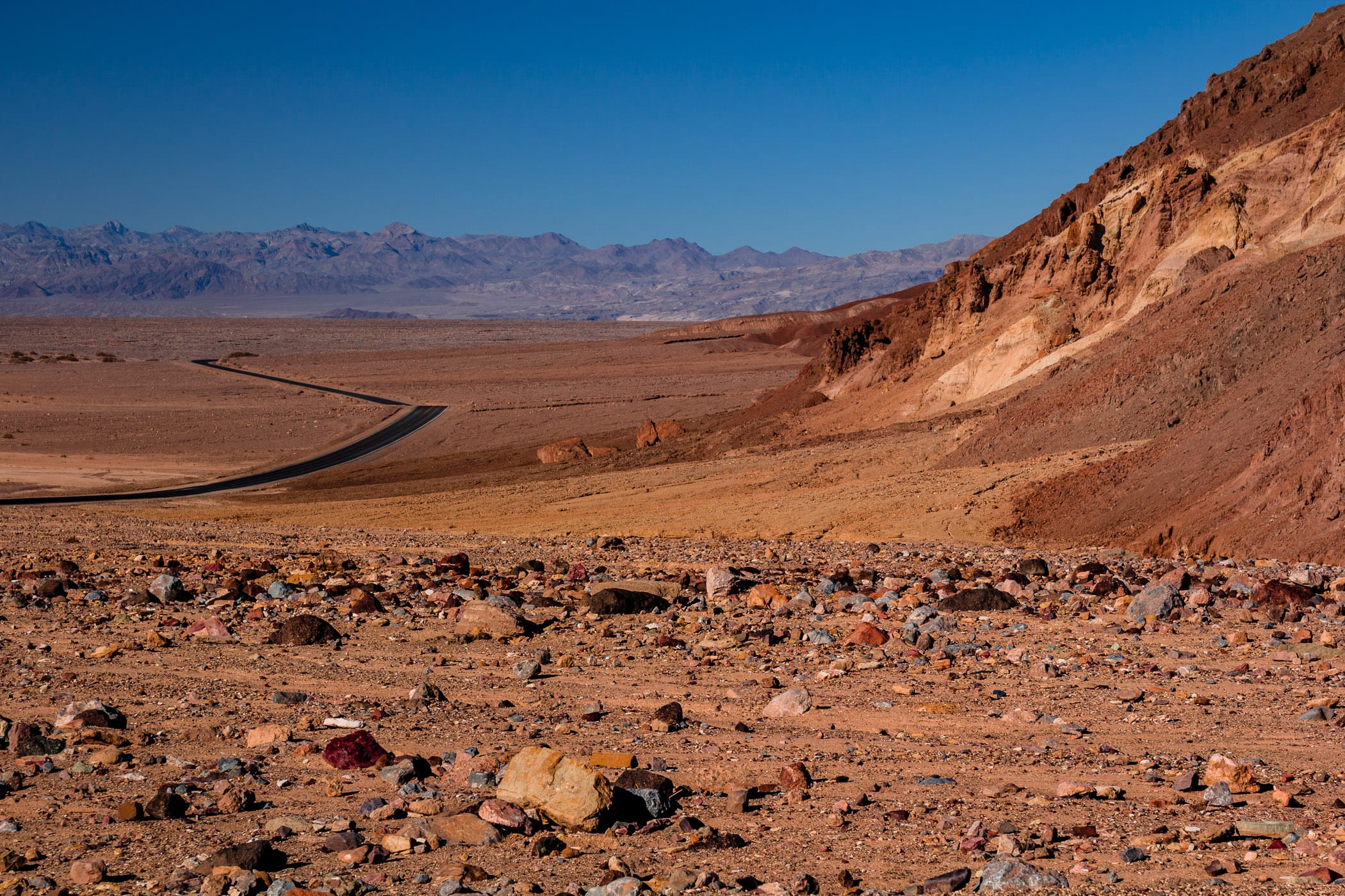 Multi-colored rocks lie on the arid desert ground at California's Death Valley National Park.