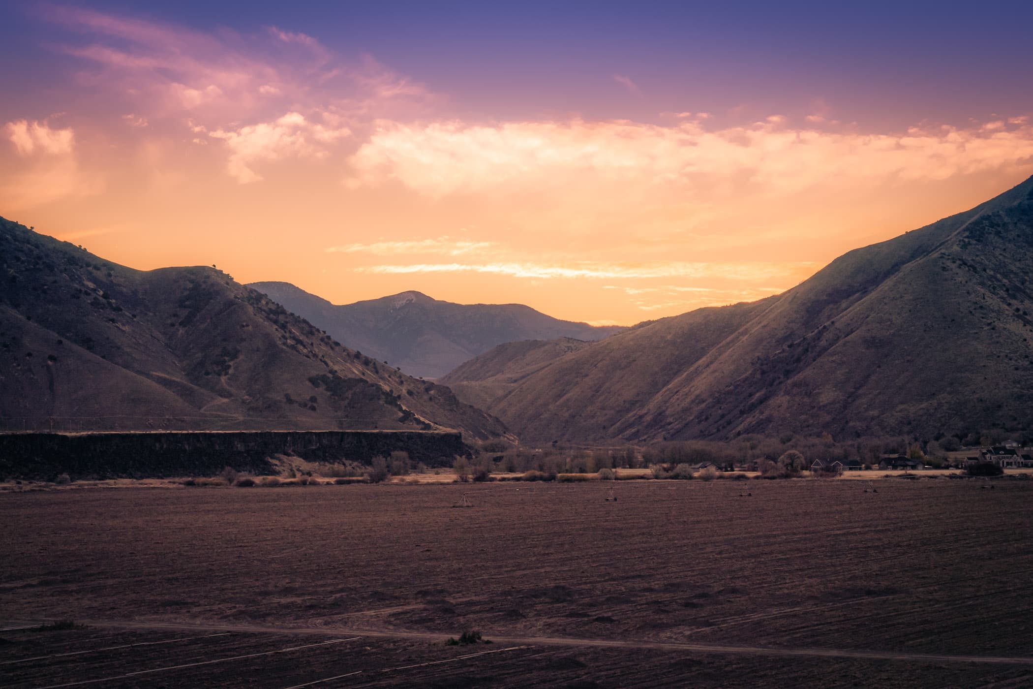 The sun rises over farmland nestled between mountains on the outskirts of Pocatello, Idaho.