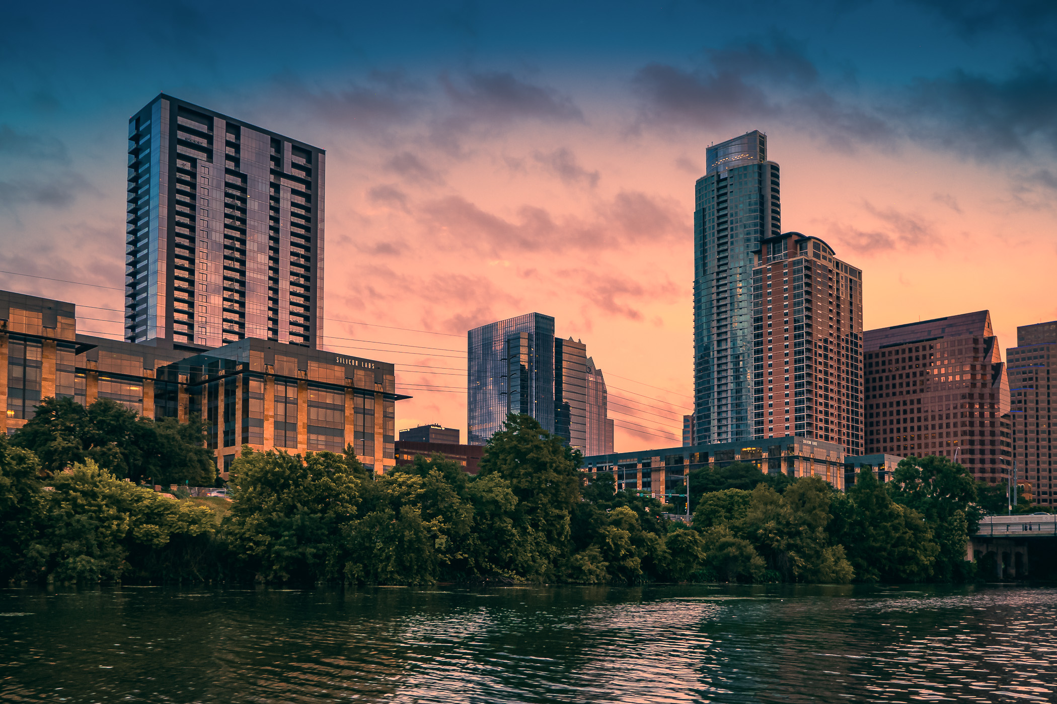 The setting sun illuminates buildings along the shoreline of Austin, Texas' Lady Bird Lake.