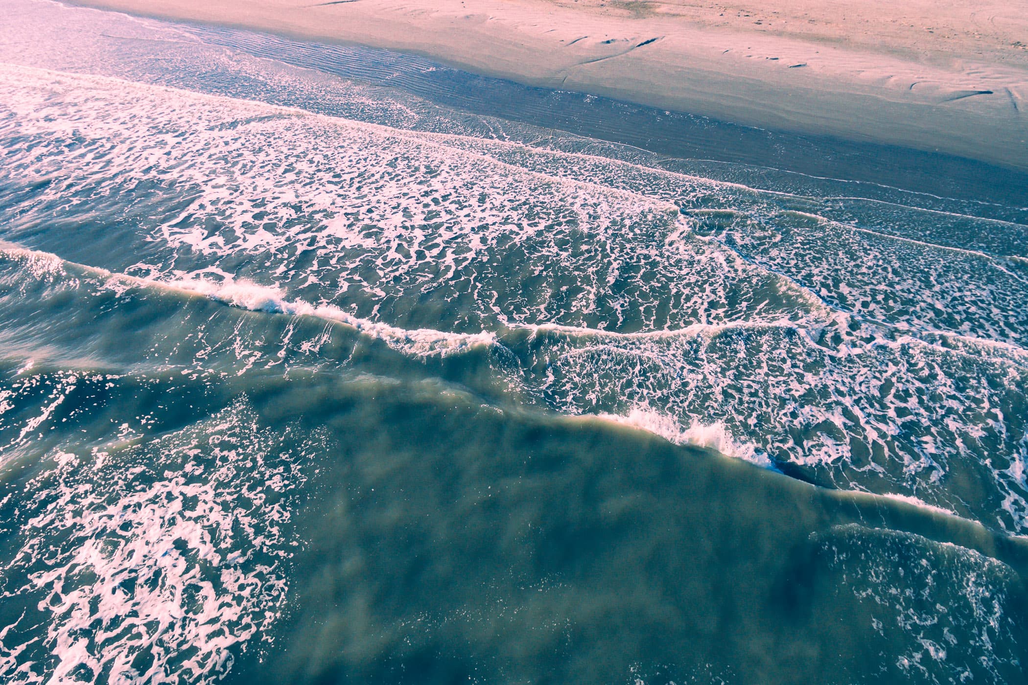 Waves crash onshore in an aerial shot of Galveston, Texas’ East Beach.