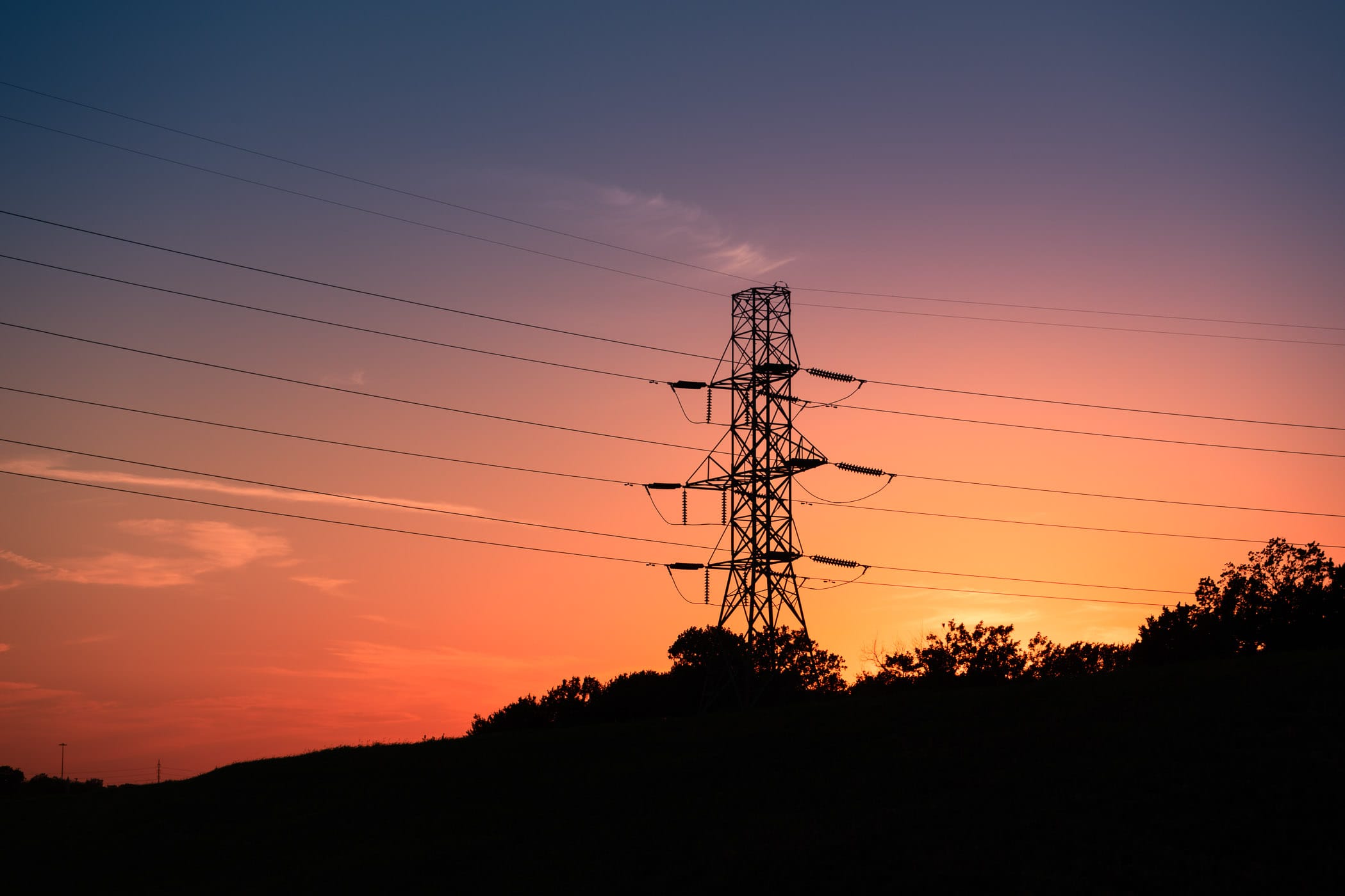 The sun sets on a electric pylon in Irving, Texas.