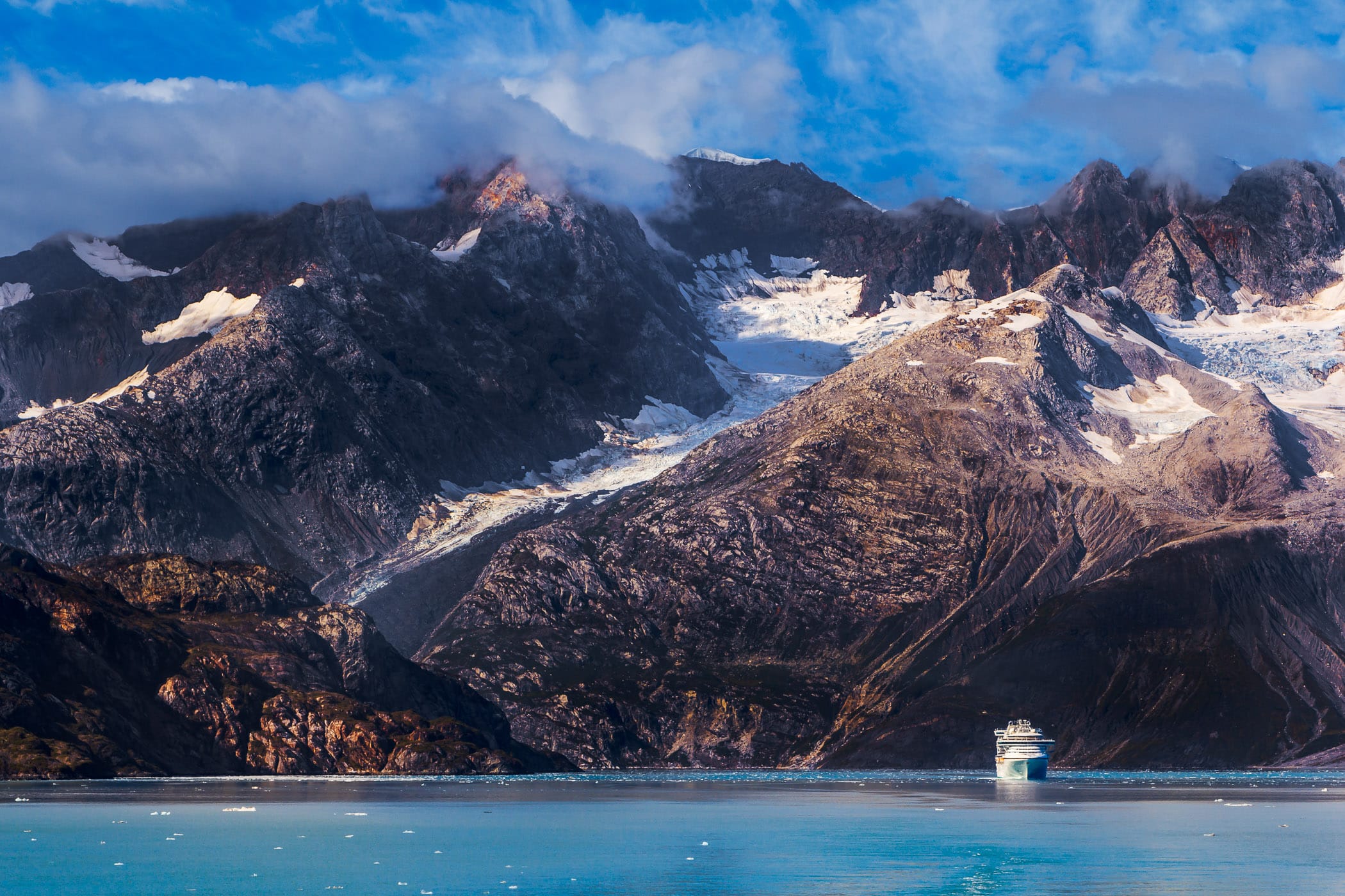 The cruise ship Sapphire Princess is dwarfed by the mountainous landscape of Alaska's Glacier Bay.