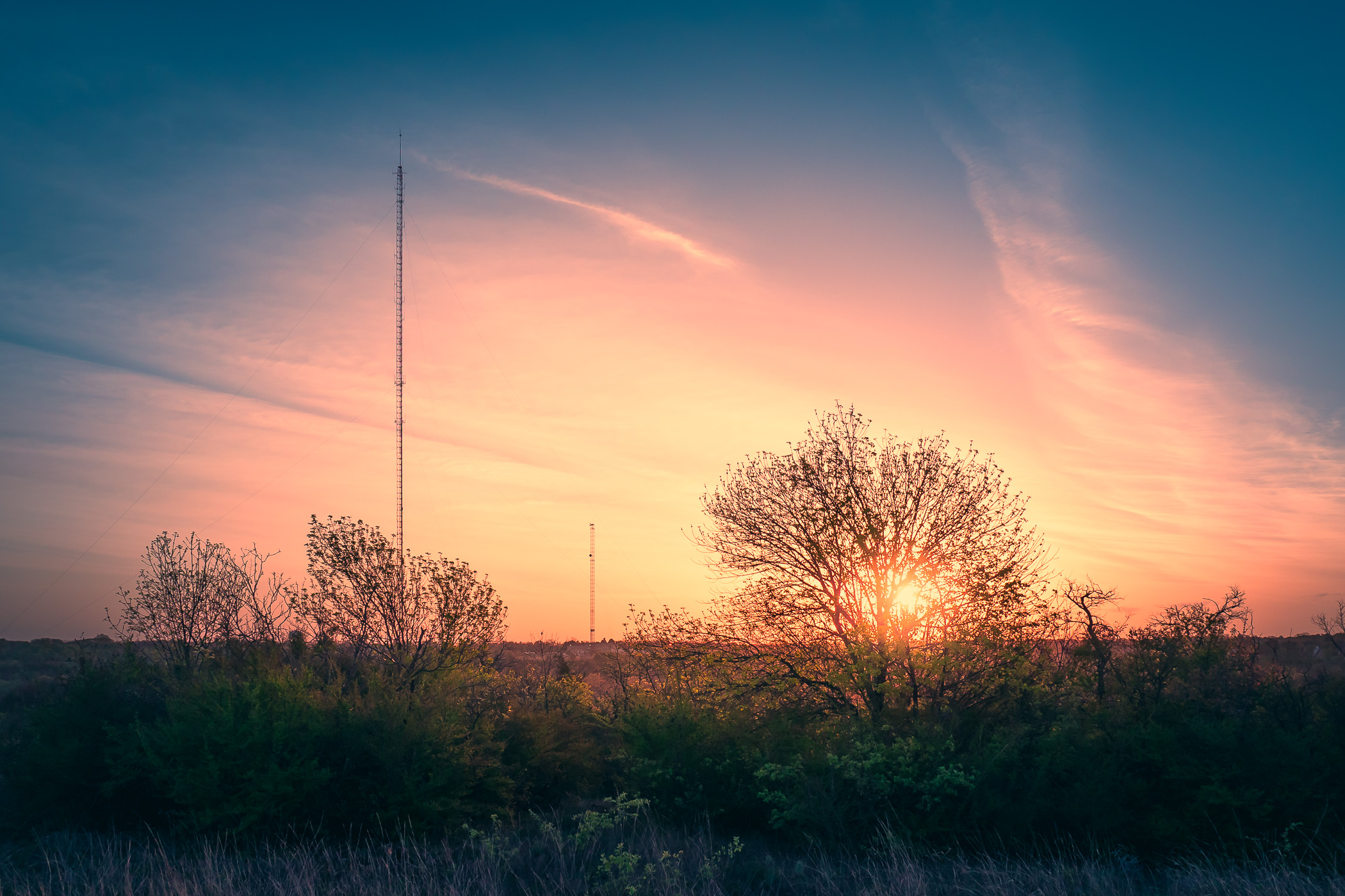 Broadcast towers rise into the sky as the sun rises over Fort Worth, Texas' Tandy Hills Natural Area.