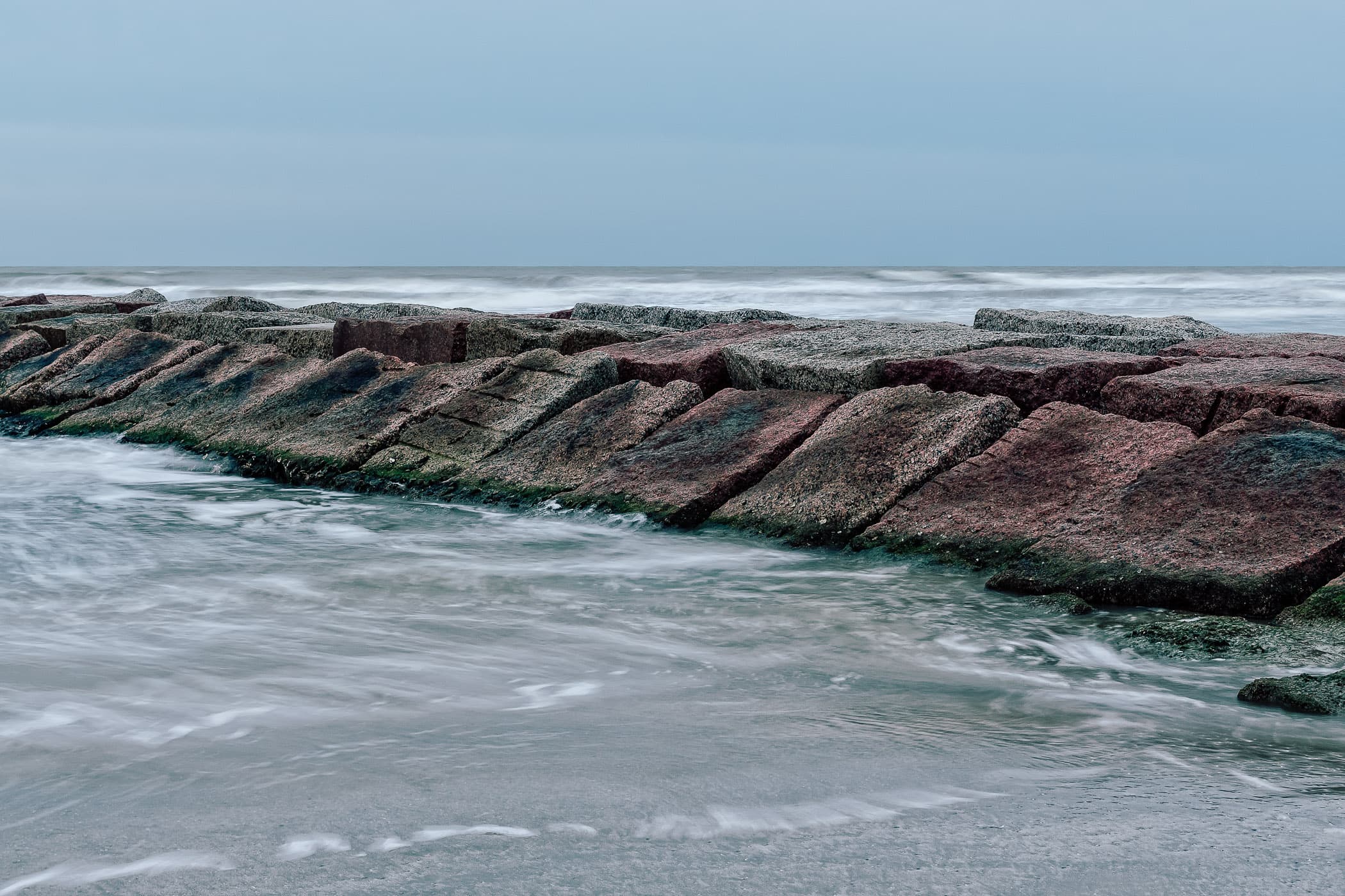 A granite jetty or, more-properly, groyne, reaches into the Gulf of Mexico from the Galveston Island, Texas, beach.