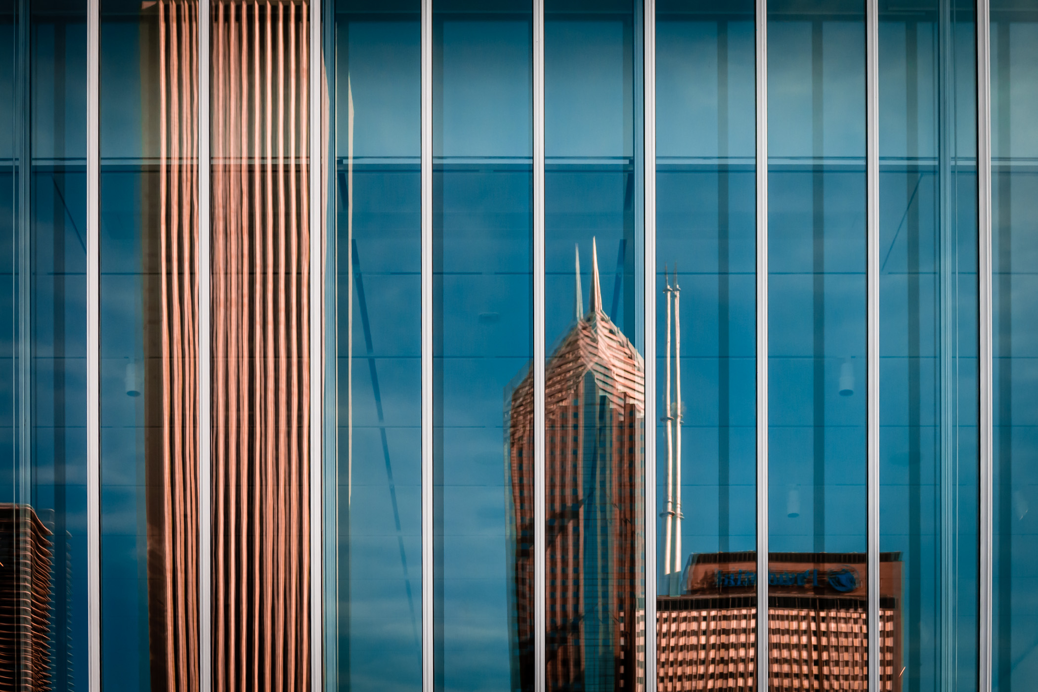 Chicago's Aon Center, Two Prudential Plaza and One Prudential Plaza are reflected in the glass windows of a nearby building.