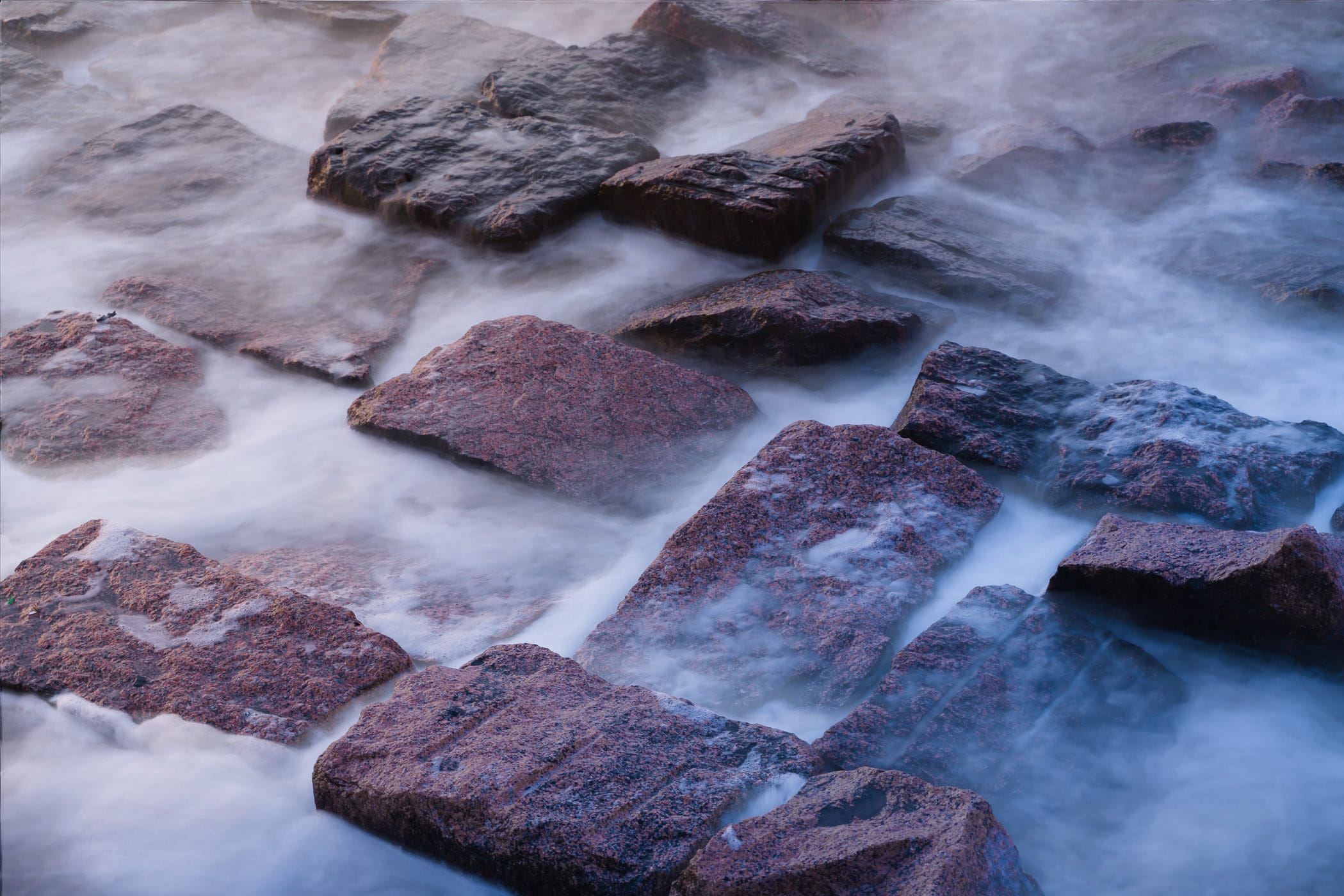 A long exposure renders the surf on these granite blocks soft and fluffy, as spotted along the Galveston, Texas, seawall.
