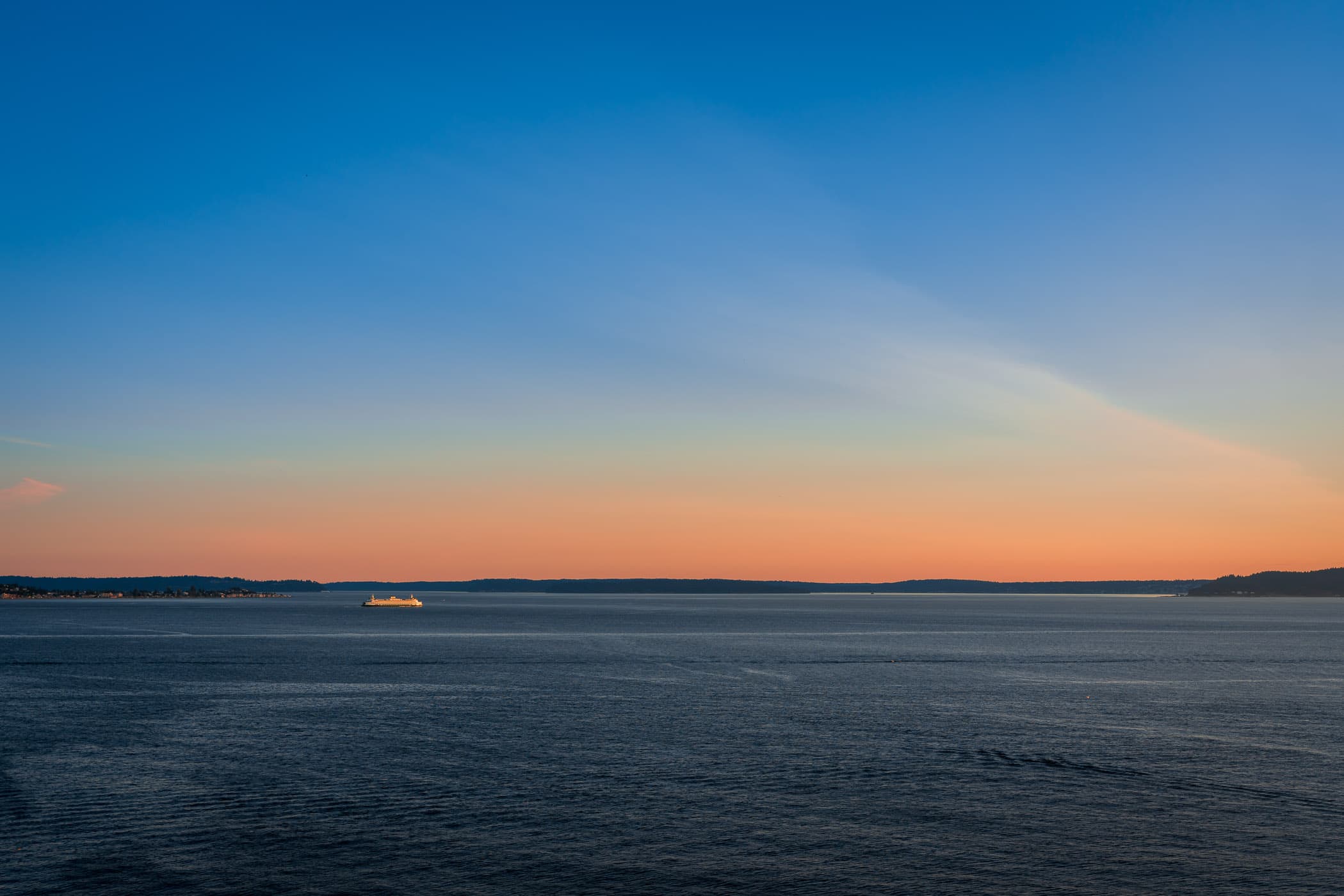 The sun sets on the Seattle-Bainbridge ferry as it crosses Puget Sound.