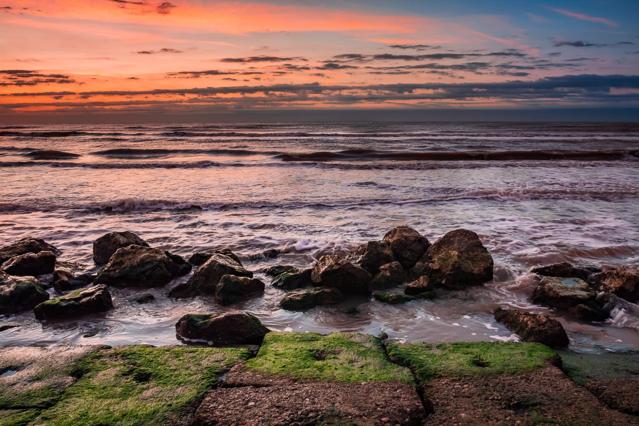 The first light of day hits granite blocks along the beach at the base of the Galveston Seawall, Galveston, Texas.