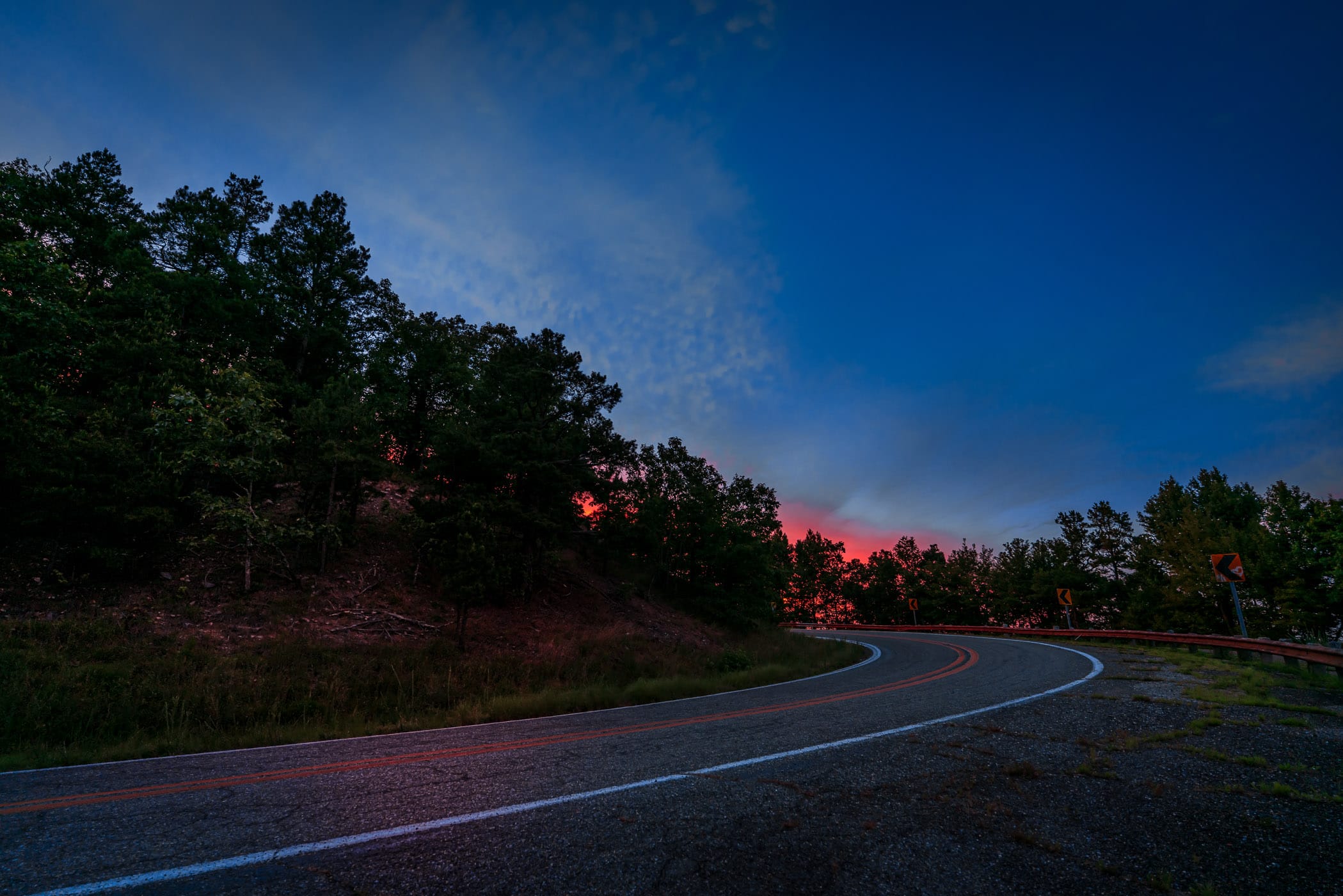 The Talimena National Scenic Byway twists through the Ouachita National Forest towards the setting sun near Mena, Arkansas.