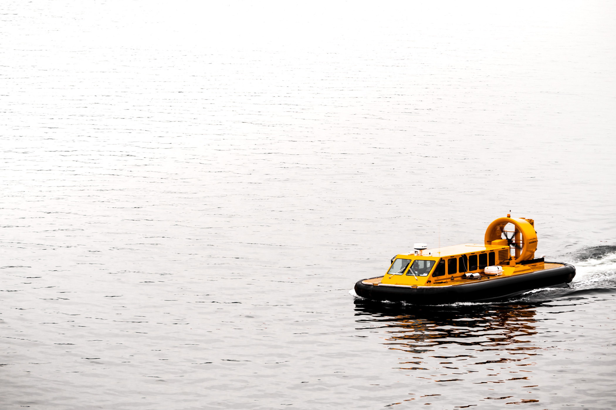 A hovercraft glides over the water of the Ketchikan, Alaska, harbor on an overcast day.